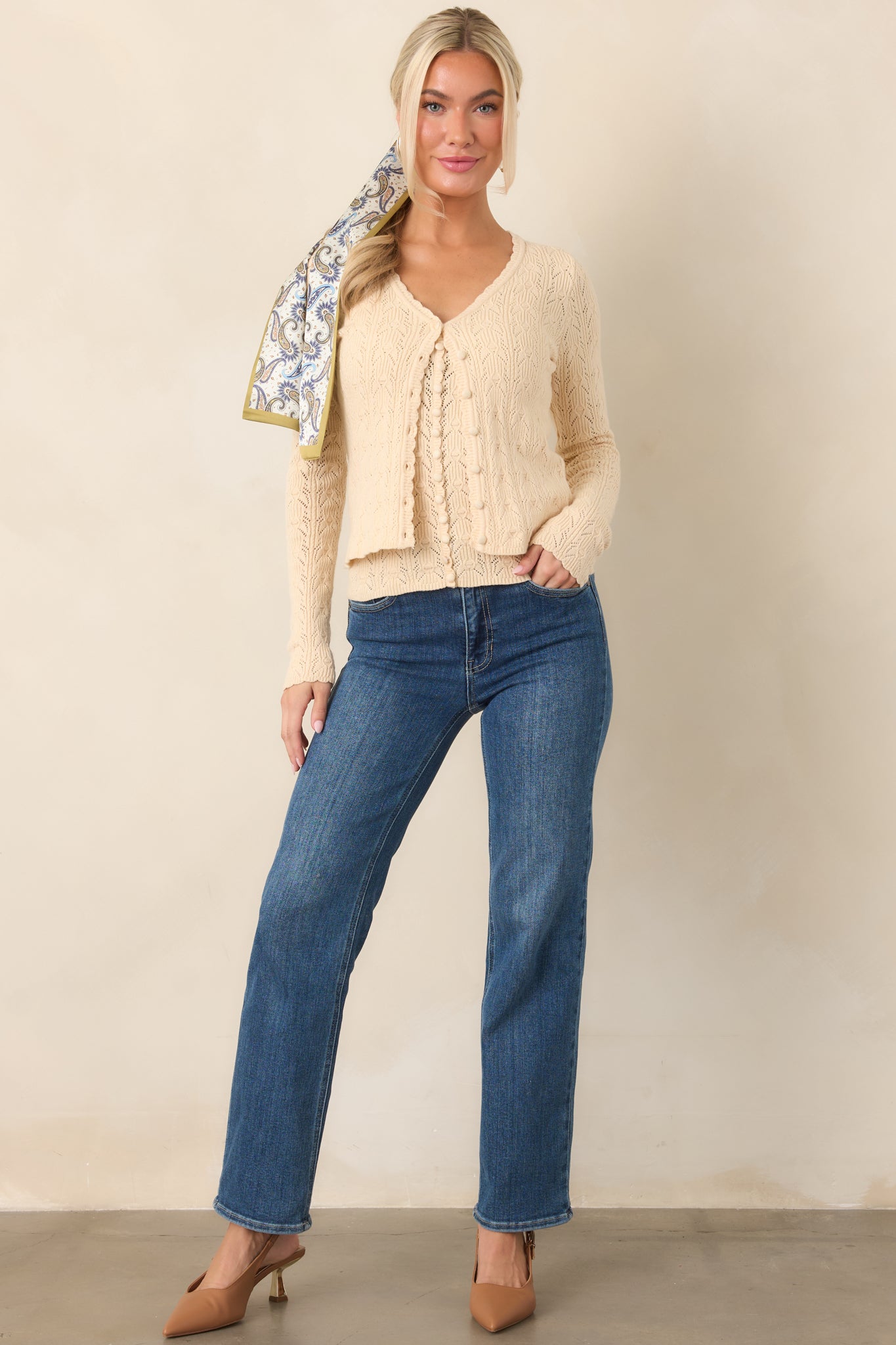 Ivory pointelle knit cardigan featuring a scalloped V-neckline, long sleeves, functional button front, and cropped silhouette.