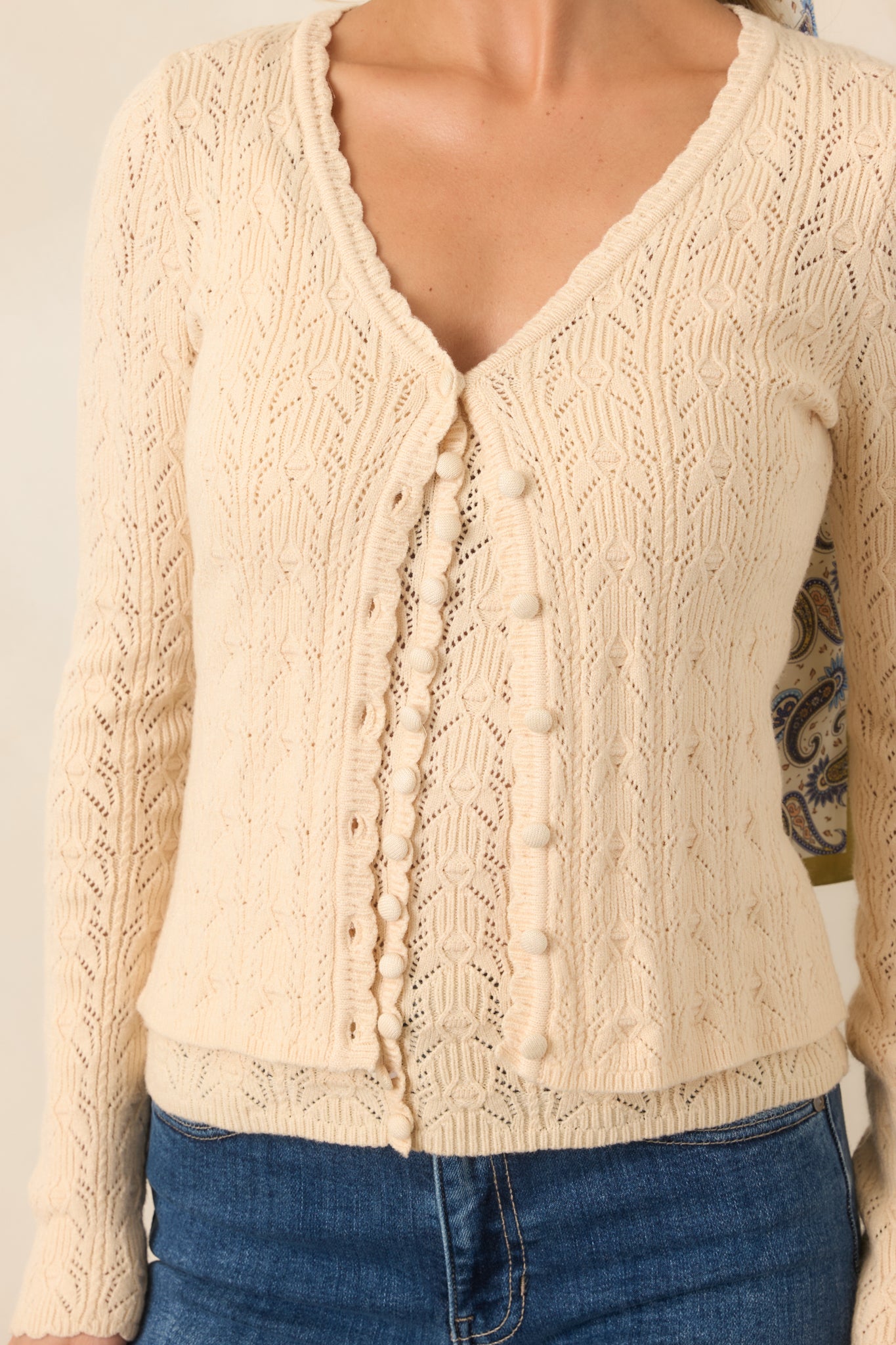Close-up of the ivory pointelle knit highlighting the intricate openwork texture, scalloped V-neckline, and button-front detailing.
