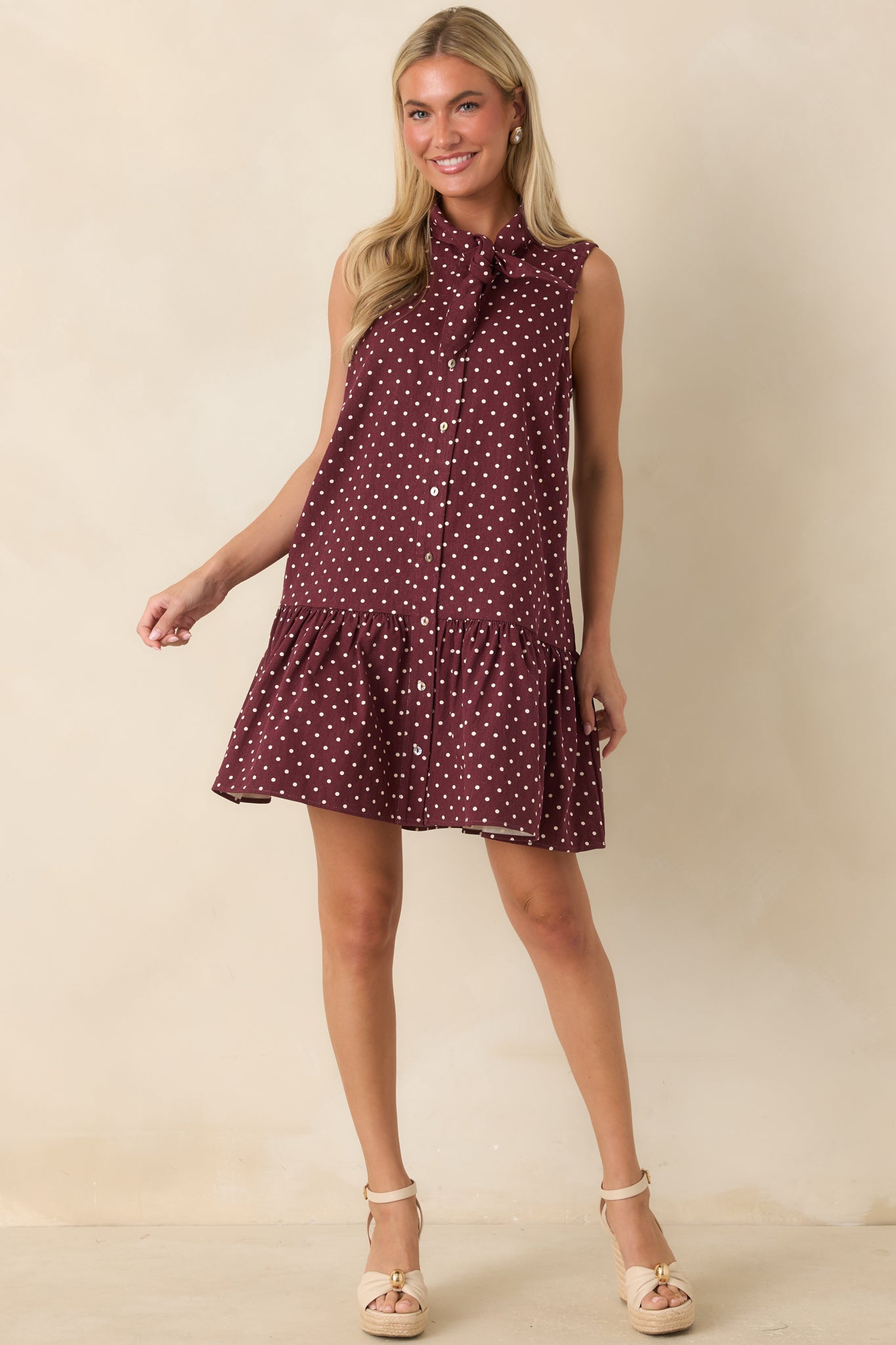 Ivory polka dot cotton dress featuring a relaxed fit, drop waist, button-front closure, and playful ruffle hem.