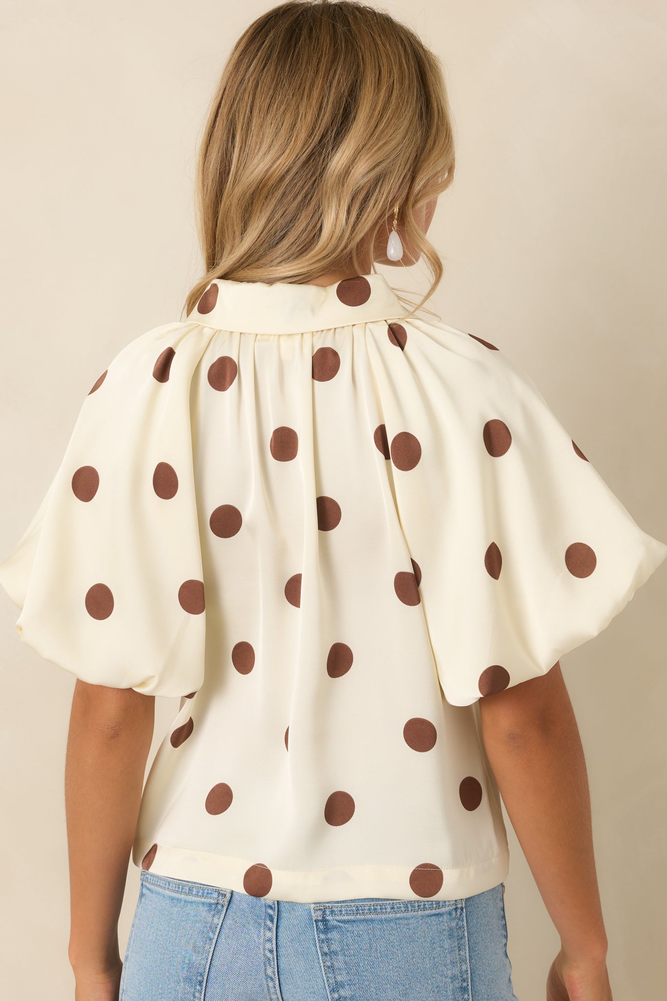 Rear view of the ivory polka dot blouse featuring gathered back yoke detailing and voluminous sleeves.
