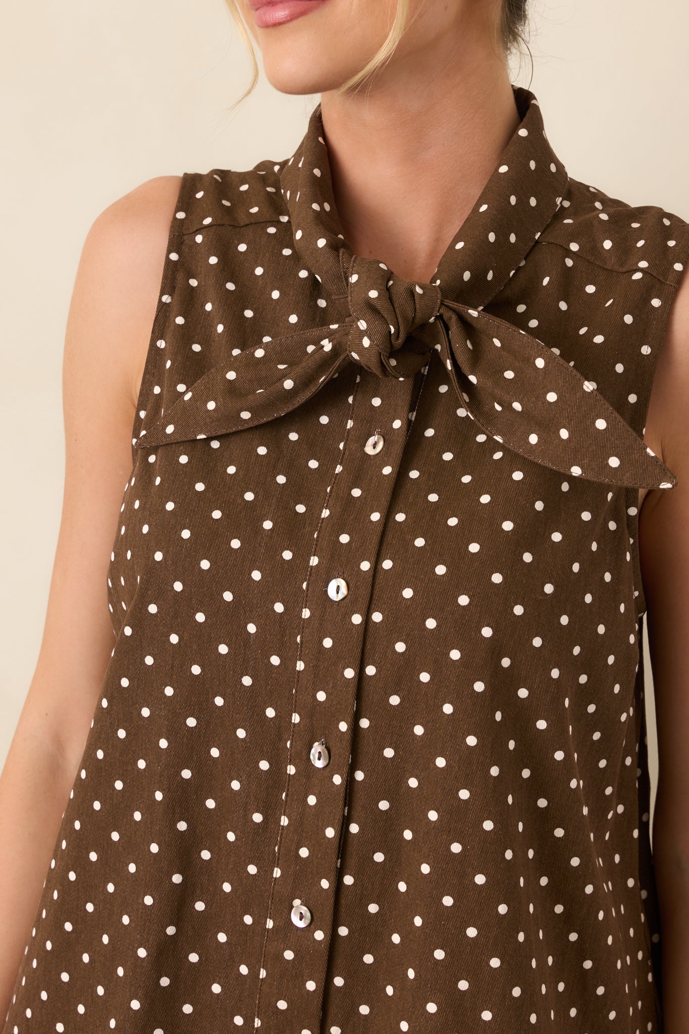 Close-up of the self-tie neckline and button-front closure against the ivory polka dot cotton fabric.