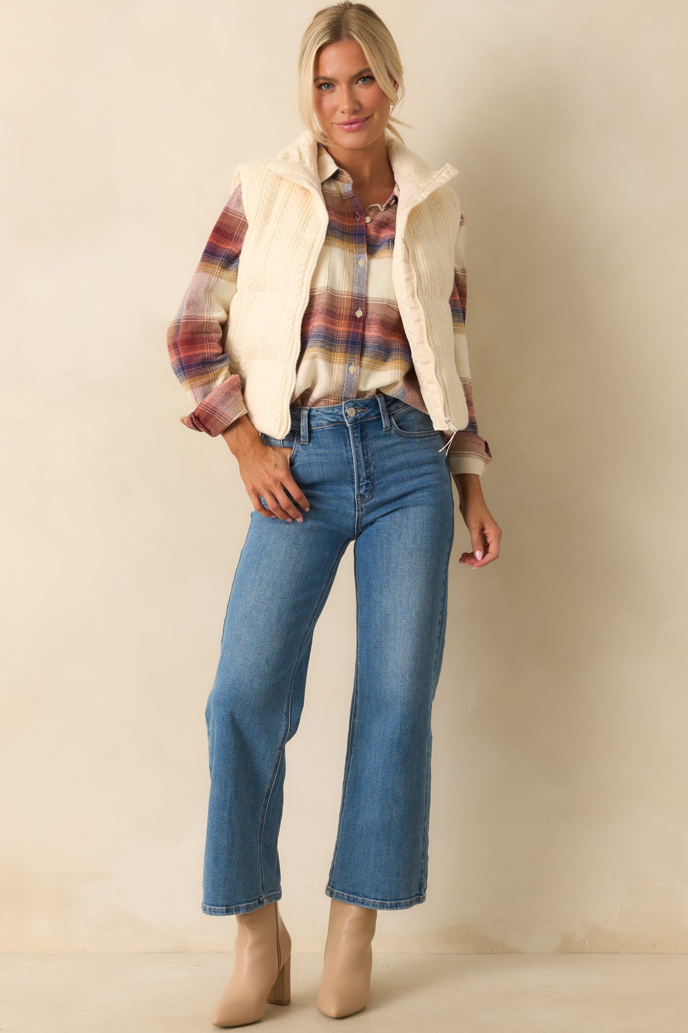 Ivory puffer vest with quilted cable knit exterior, high stand collar, and sleeveless design.