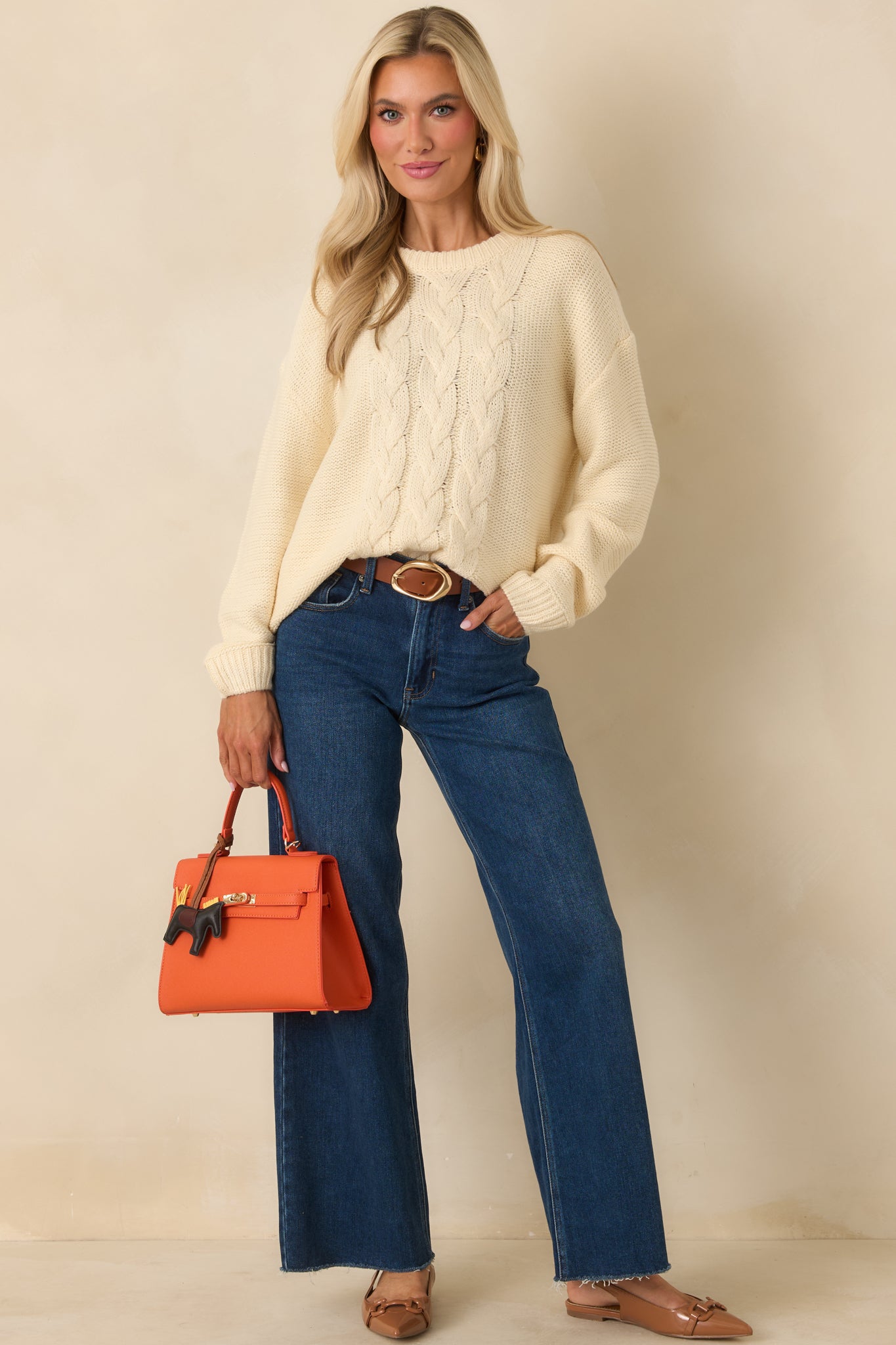 Ivory pullover sweater in a soft knit with a classic cable knit pattern centered down the front and a relaxed silhouette.