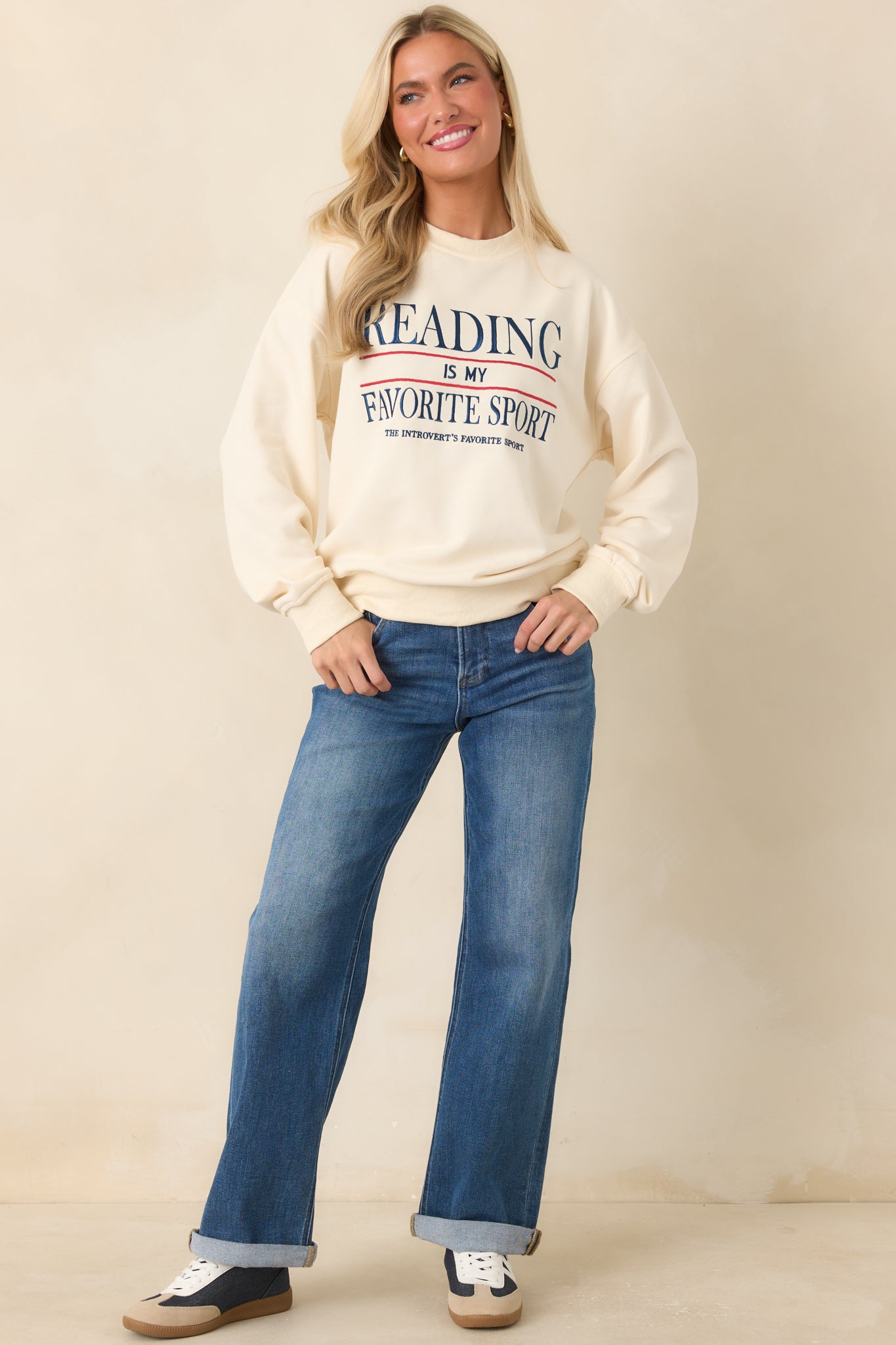 Ivory pullover showcasing navy and red embroidered lettering with ribbed trim along the neckline, cuffs, and hem.