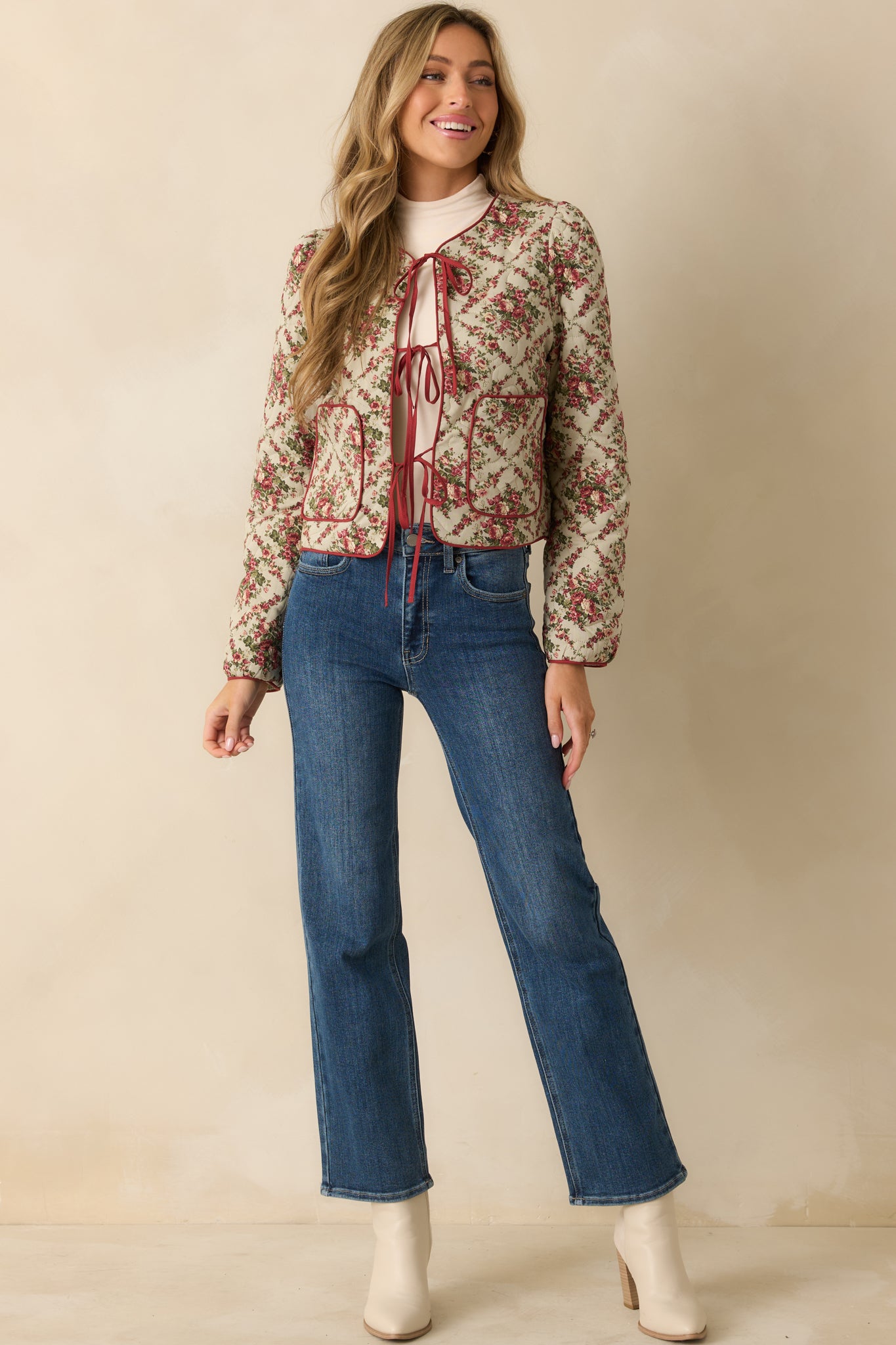 Ivory quilted jacket with red contrast binding, floral print, and front tie closure for a relaxed, structured look.