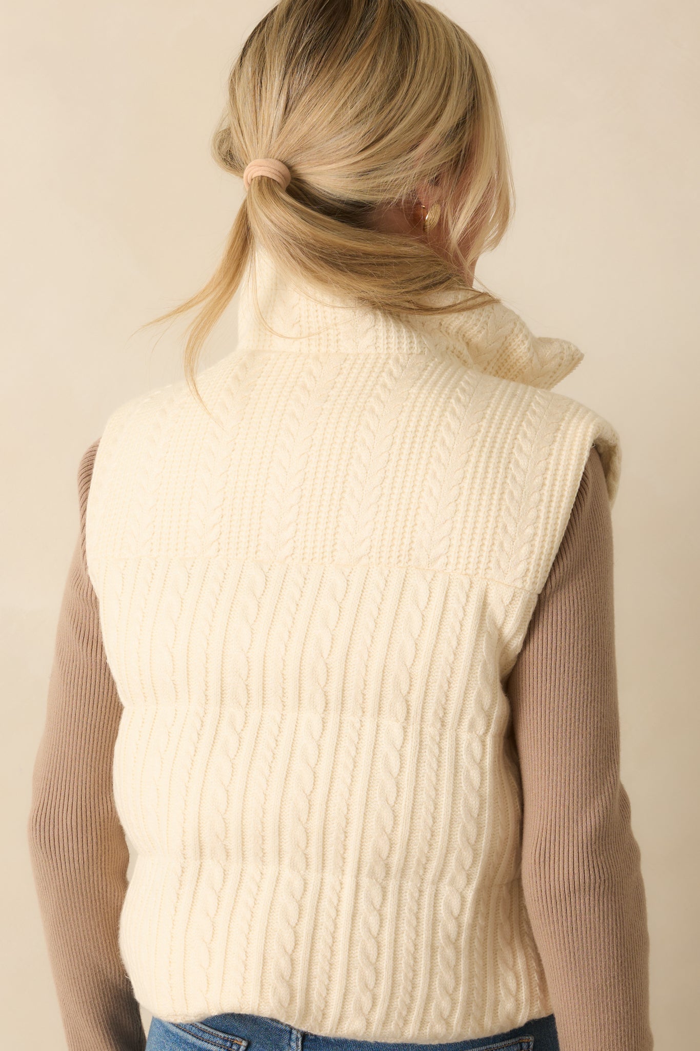 Rear view of the ivory quilted puffer vest showing sleeveless design and padded body.