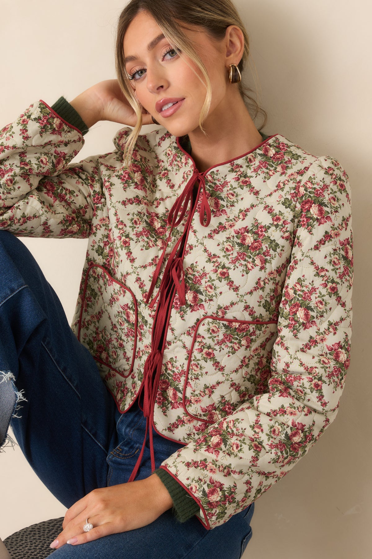 Ivory quilted jacket with a vintage-inspired rose print, deep red piping, and a front tie closure.

