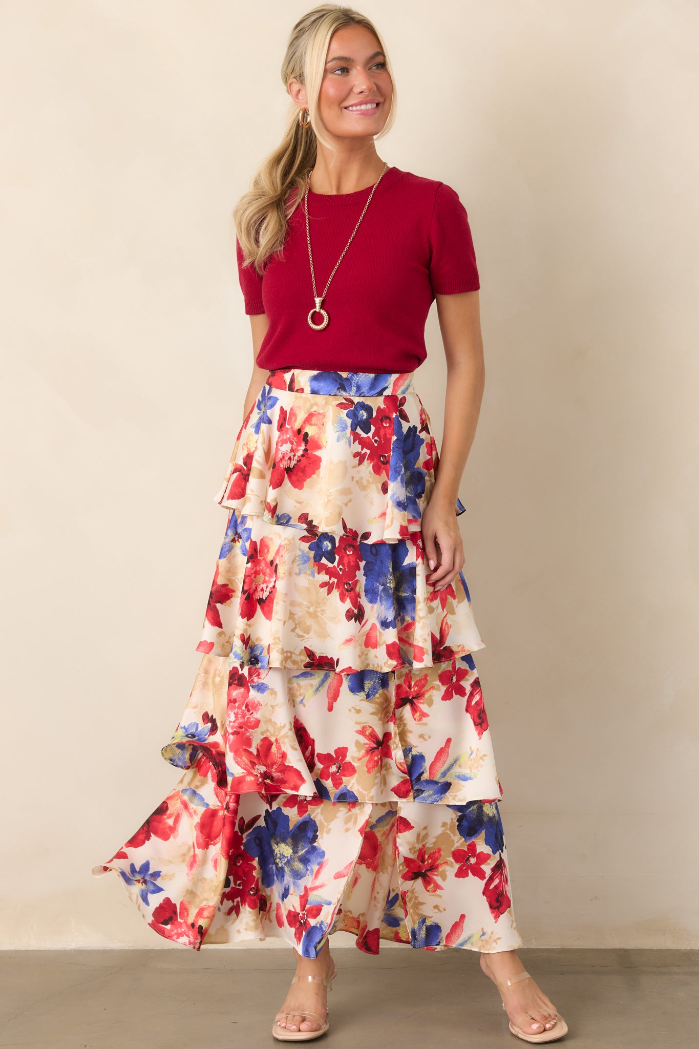 Ivory and red floral print maxi skirt featuring cascading tiers, an elastic back waistband, and a flowing silhouette with vibrant allover blooms.