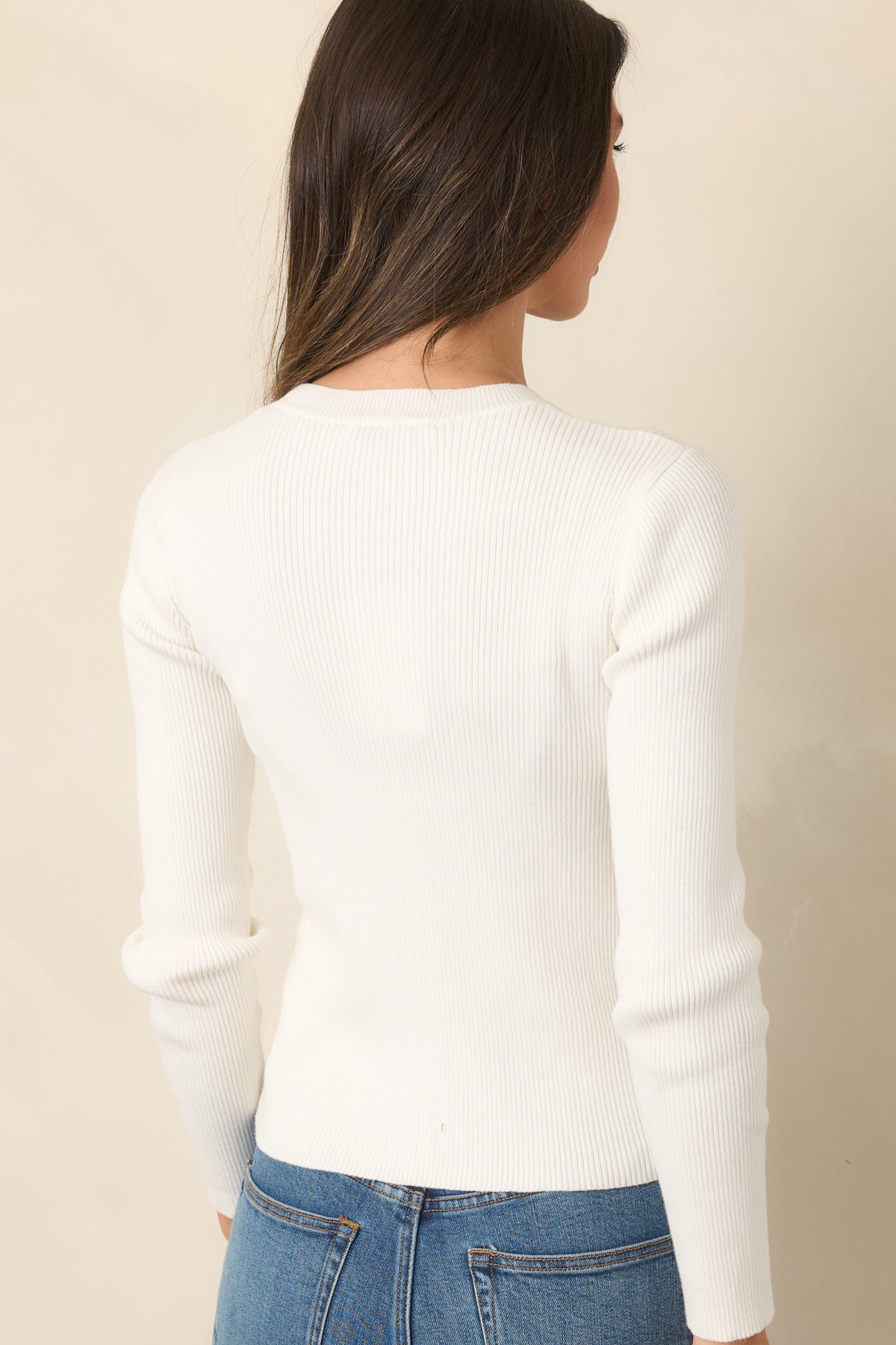 Back view of ivory ribbed cotton knit top featuring a fitted silhouette, fine vertical ribbing, and long sleeves.