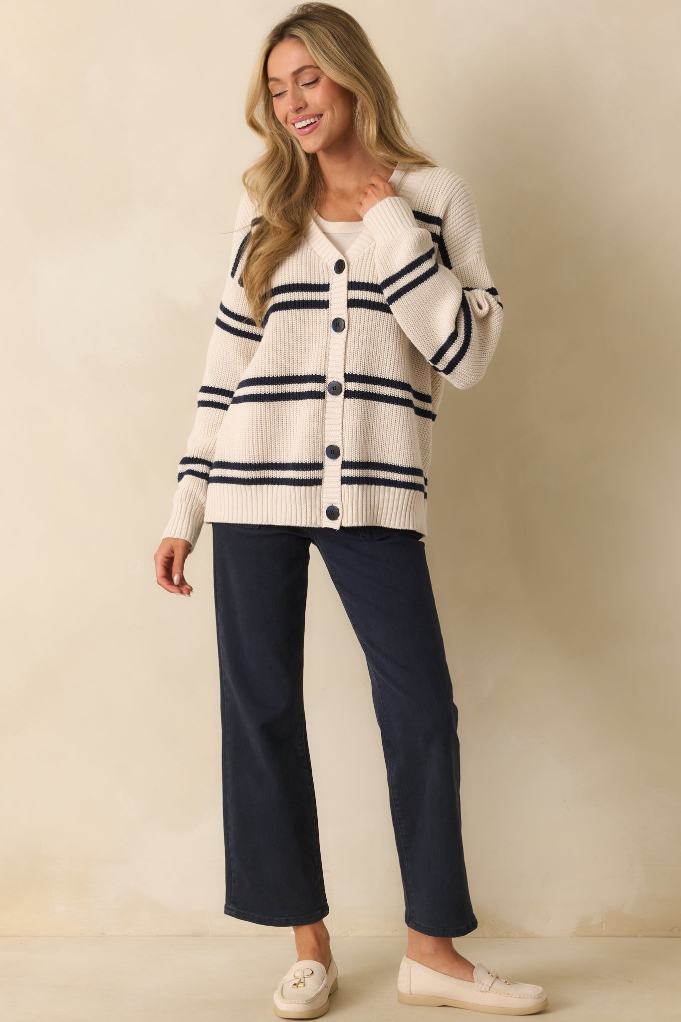 Ivory ribbed knit cardigan with horizontal navy stripes, V-neckline, and functional button front closure.
