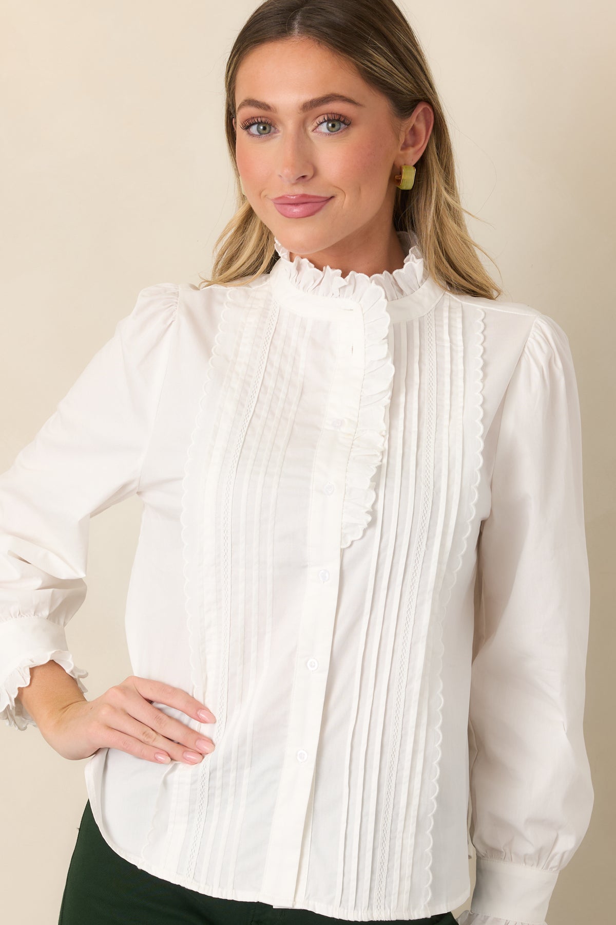 Ivory blouse showcasing the delicate ruffle-trimmed shoulders and fine vertical pintuck detailing across the front.