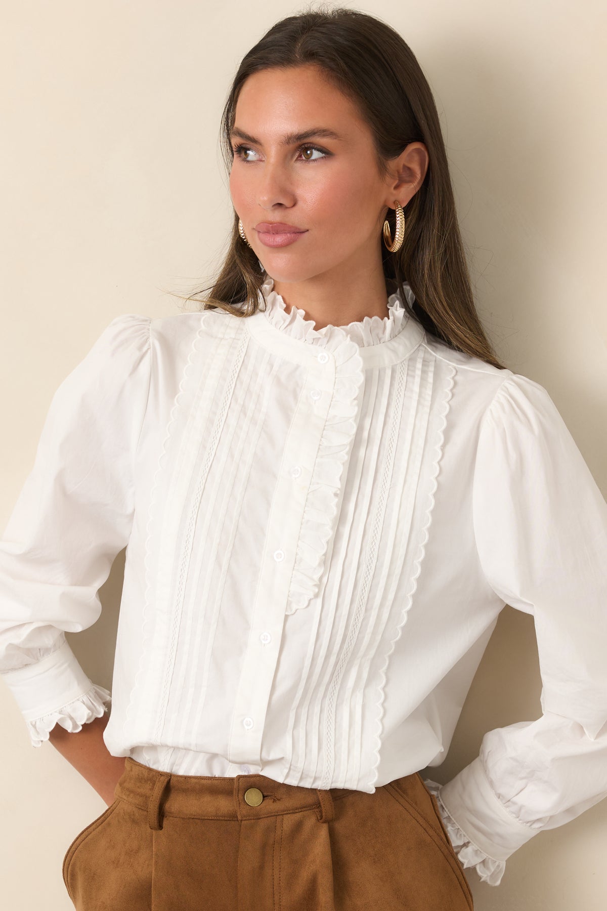 Ivory blouse highlighting the ruffled high neckline and vertical pintuck detailing.