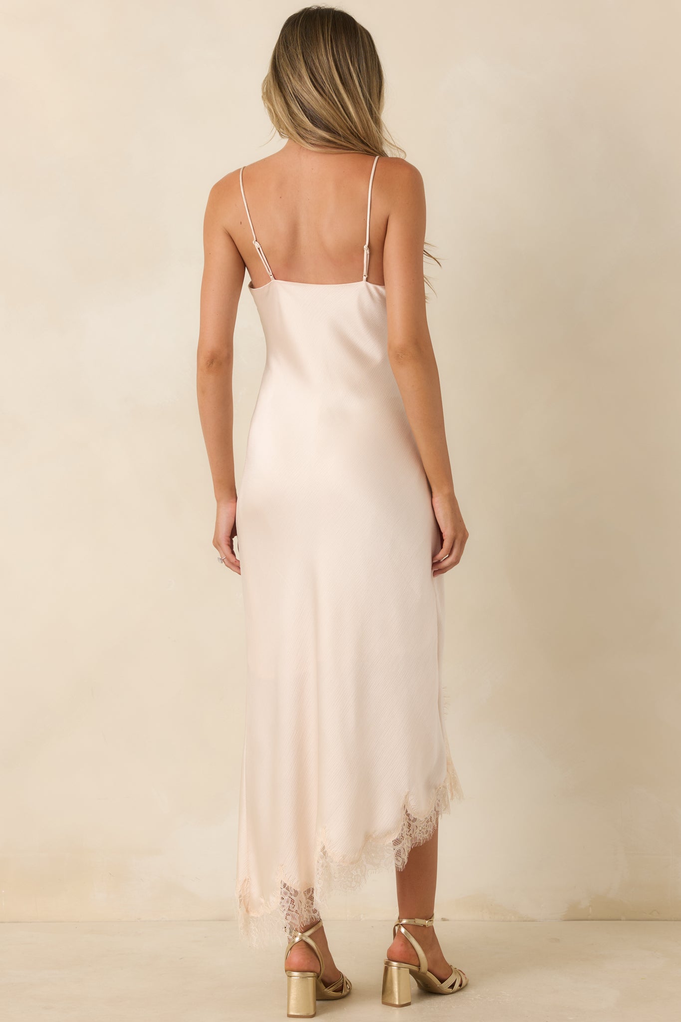 Back of the ivory satin slip dress featuring adjustable straps and a smooth bias-cut silhouette.