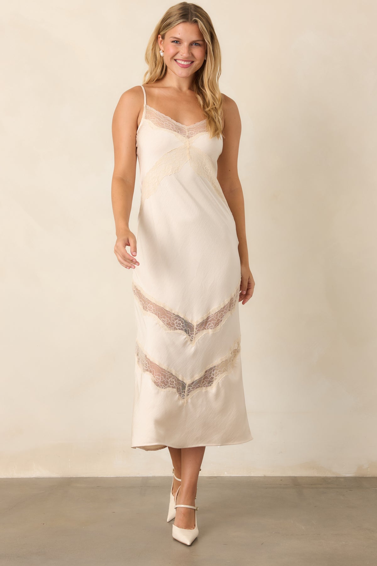 Ivory satin dress with a fluid silhouette, adjustable straps, lace-trimmed V-neckline, and chevron lace insets.