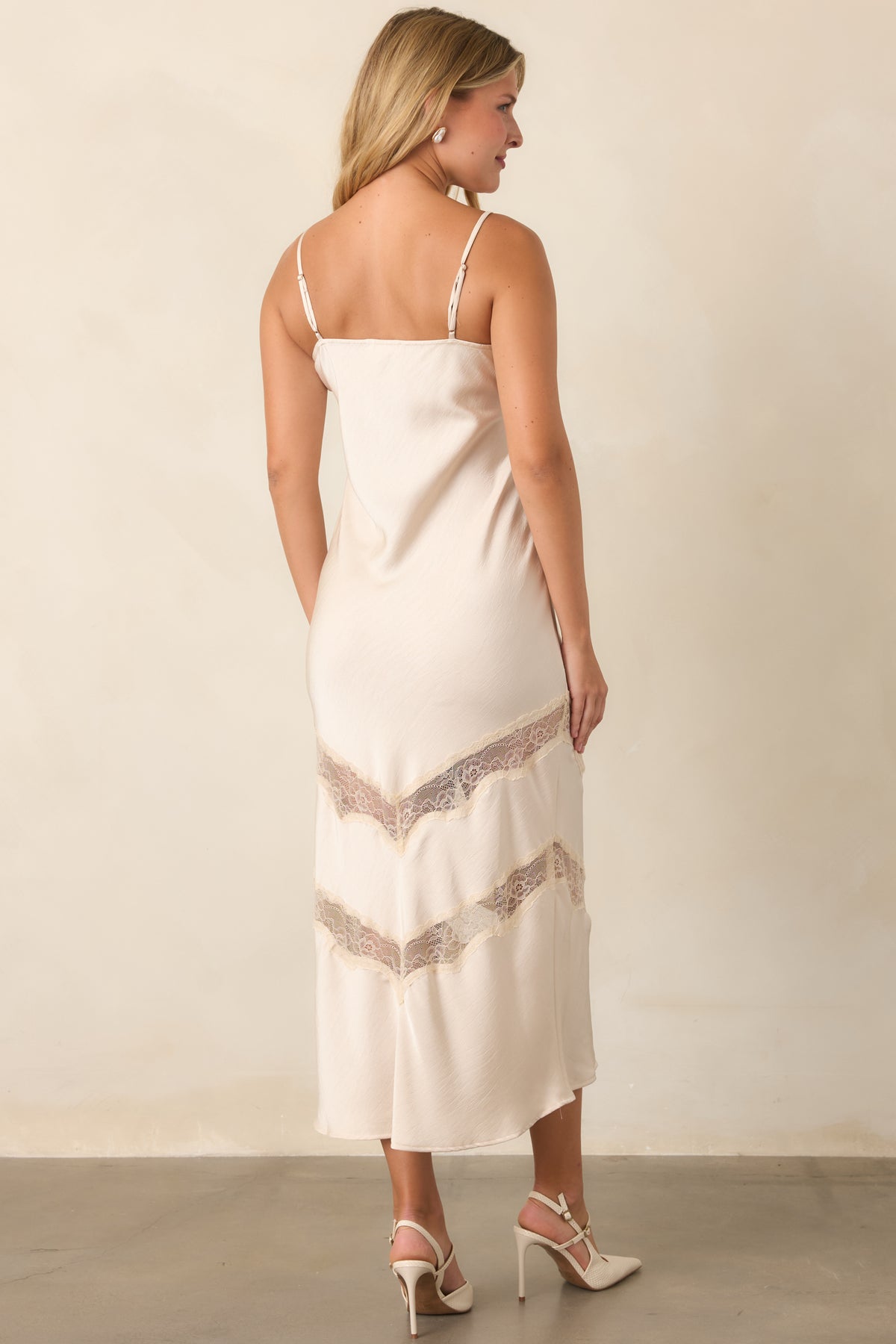 Rear view of the ivory satin dress showcasing its slender straps, fluid shape, and softly draped silhouette.
