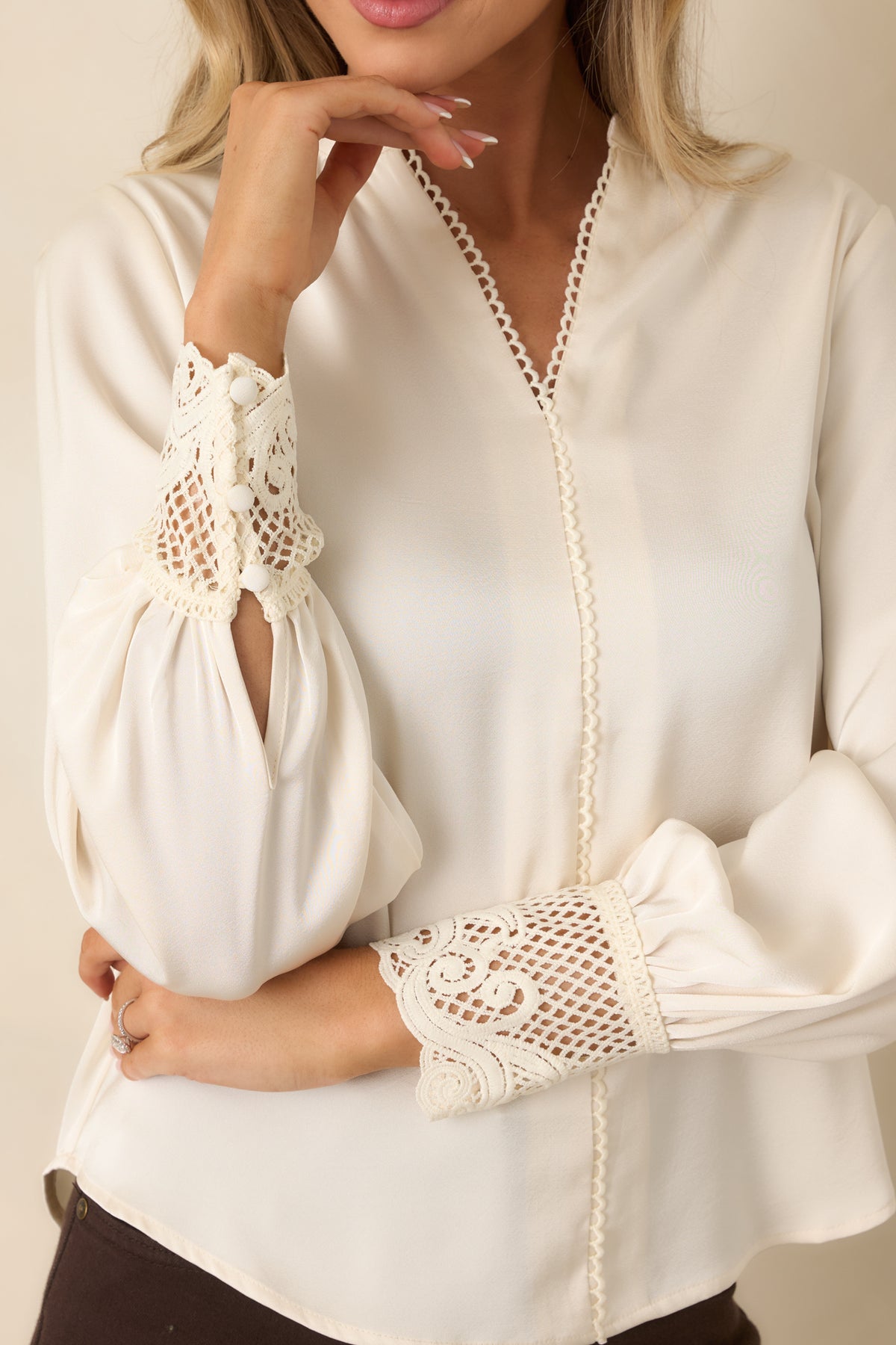 Delicate loop trim along the split V-neckline contrasts with the sheer scalloped lace cuffs of the ivory satin blouse.