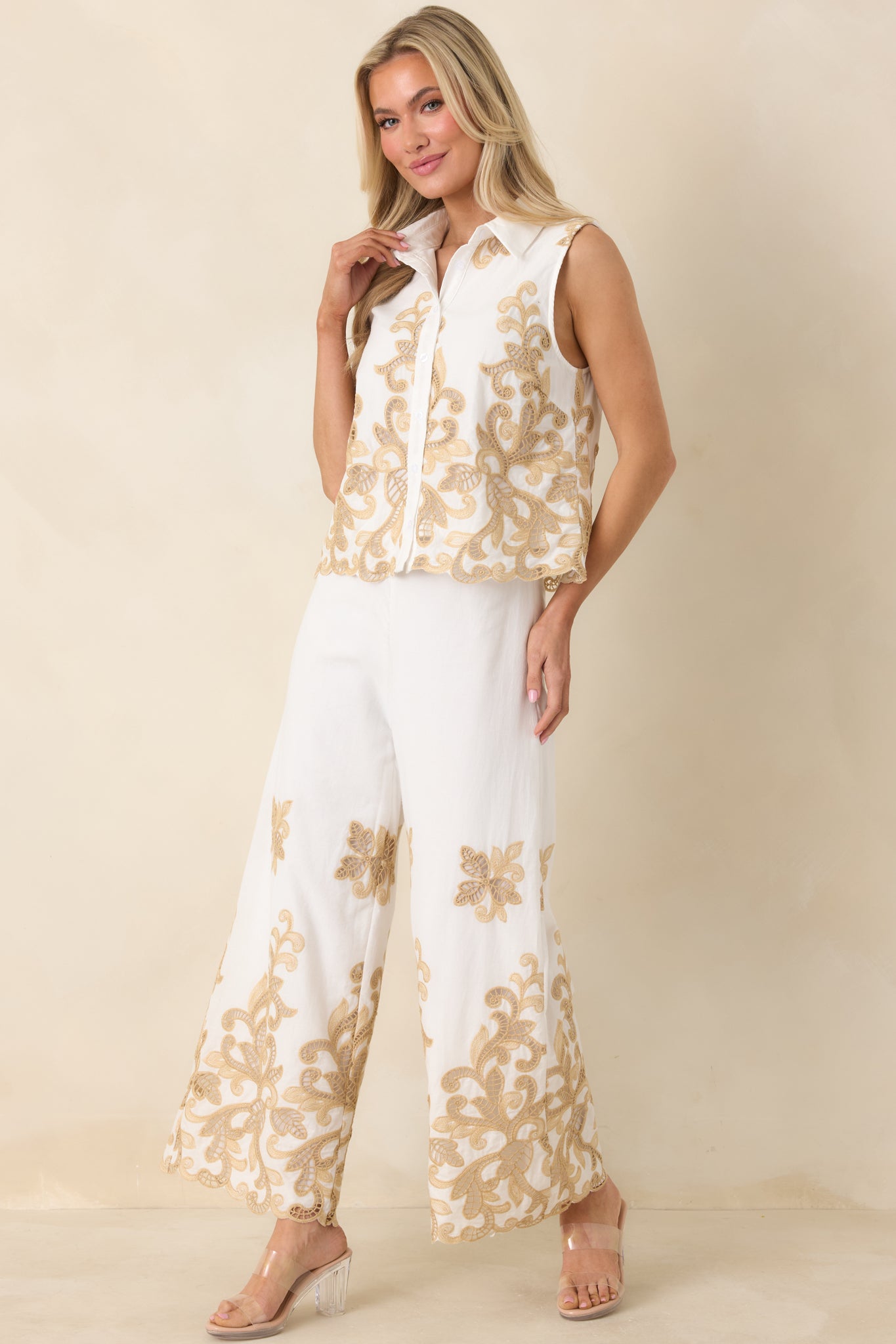 Ivory sleeveless button-front top with collared neckline and scalloped hem.