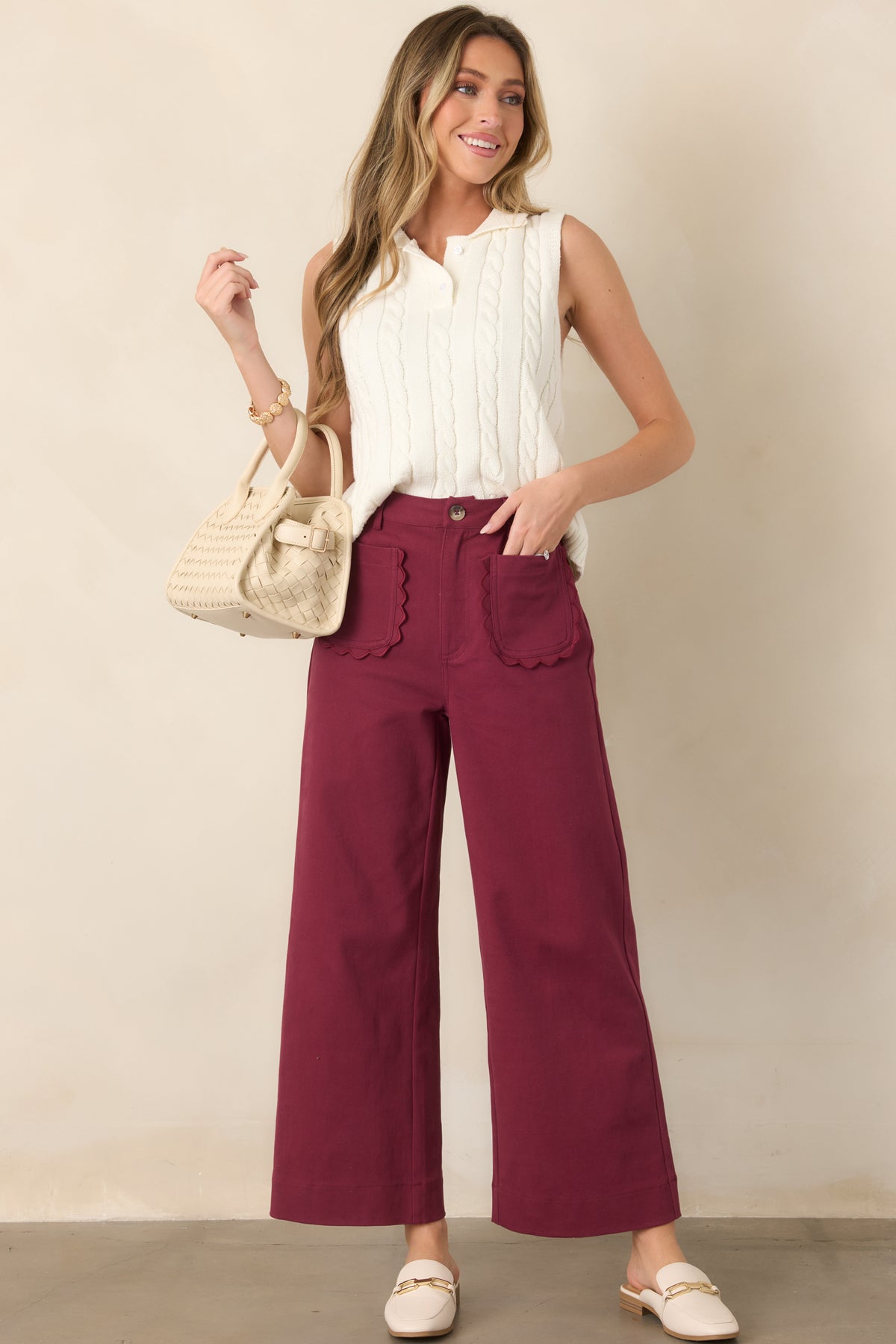 Sleeveless ivory knit vest showcasing a classic polo collar, functional front buttons, dimensional cable-knit texture, and softly structured shape.