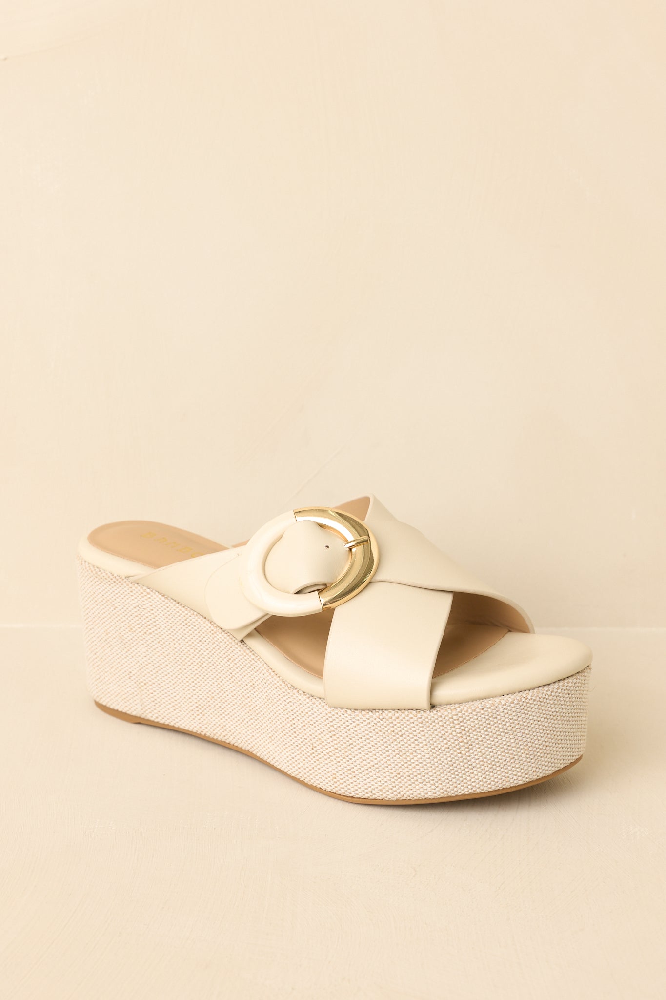 Close cropped angle of ivory slip-on wedge sandals highlighting the smooth upper and textured platform sole.