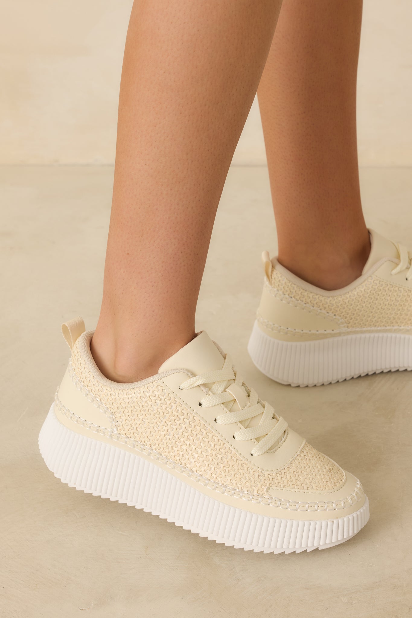 Cropped view of the ivory sneakers highlighting the knit upper and lace-up front.