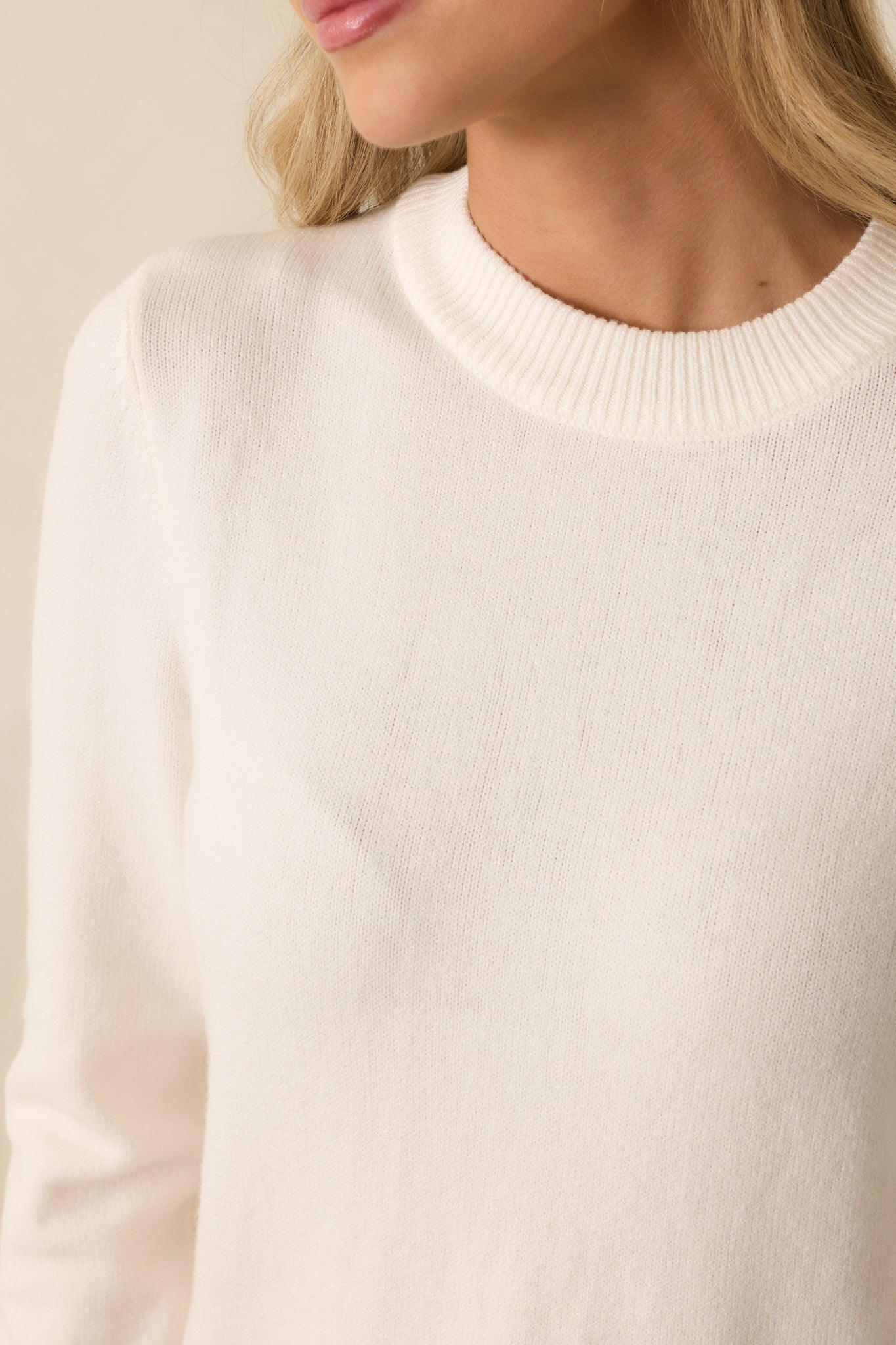 Detailed view of the ribbed hemlines and knit texture on the ivory sweater.
