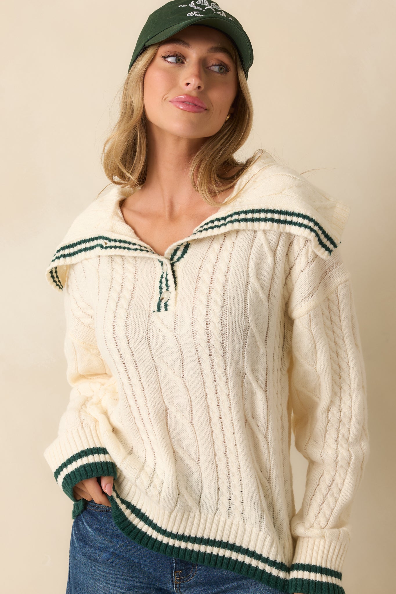 Cropped front view highlighting the relaxed fit, collar, and green contrast trim on the ivory sweater.