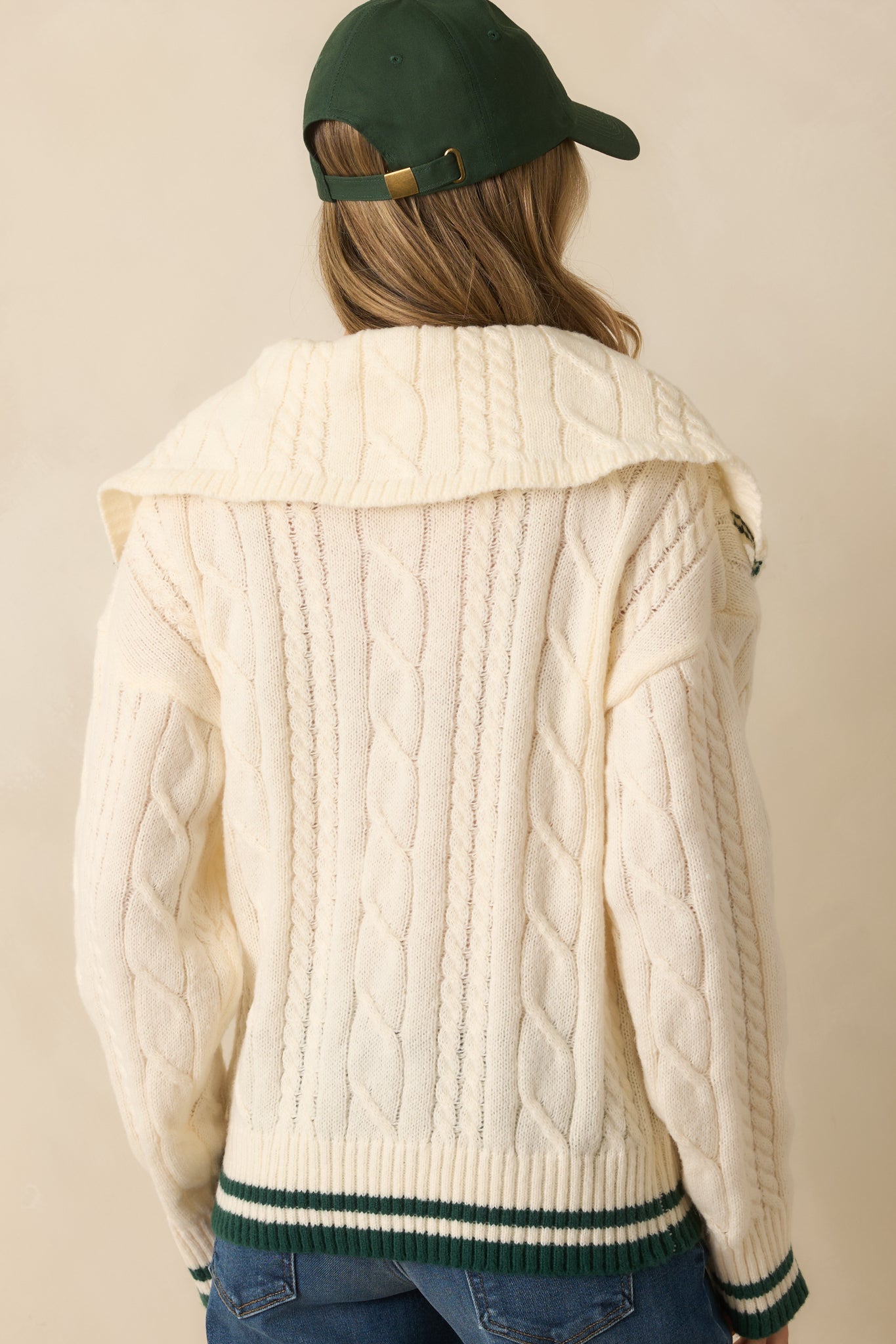 Rear view of the ivory sweater with smooth knit back, ribbed hem, and long sleeves.