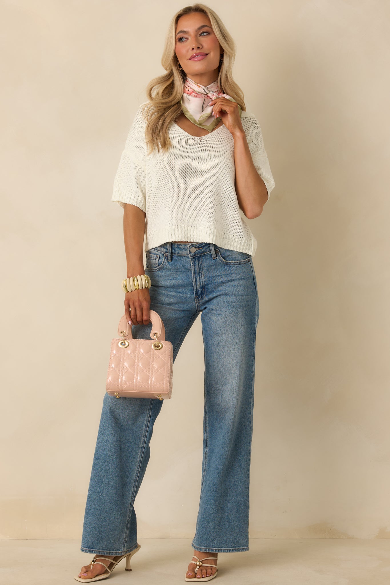 Soft ivory sweater showcasing short sleeves, a collared V-neckline, and a ribbed hem that adds gentle definition.