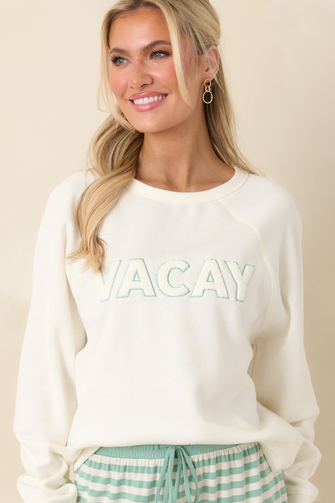 Crew neckline and raglan seam detail highlighted on ivory fabric with soft ribbed trim.