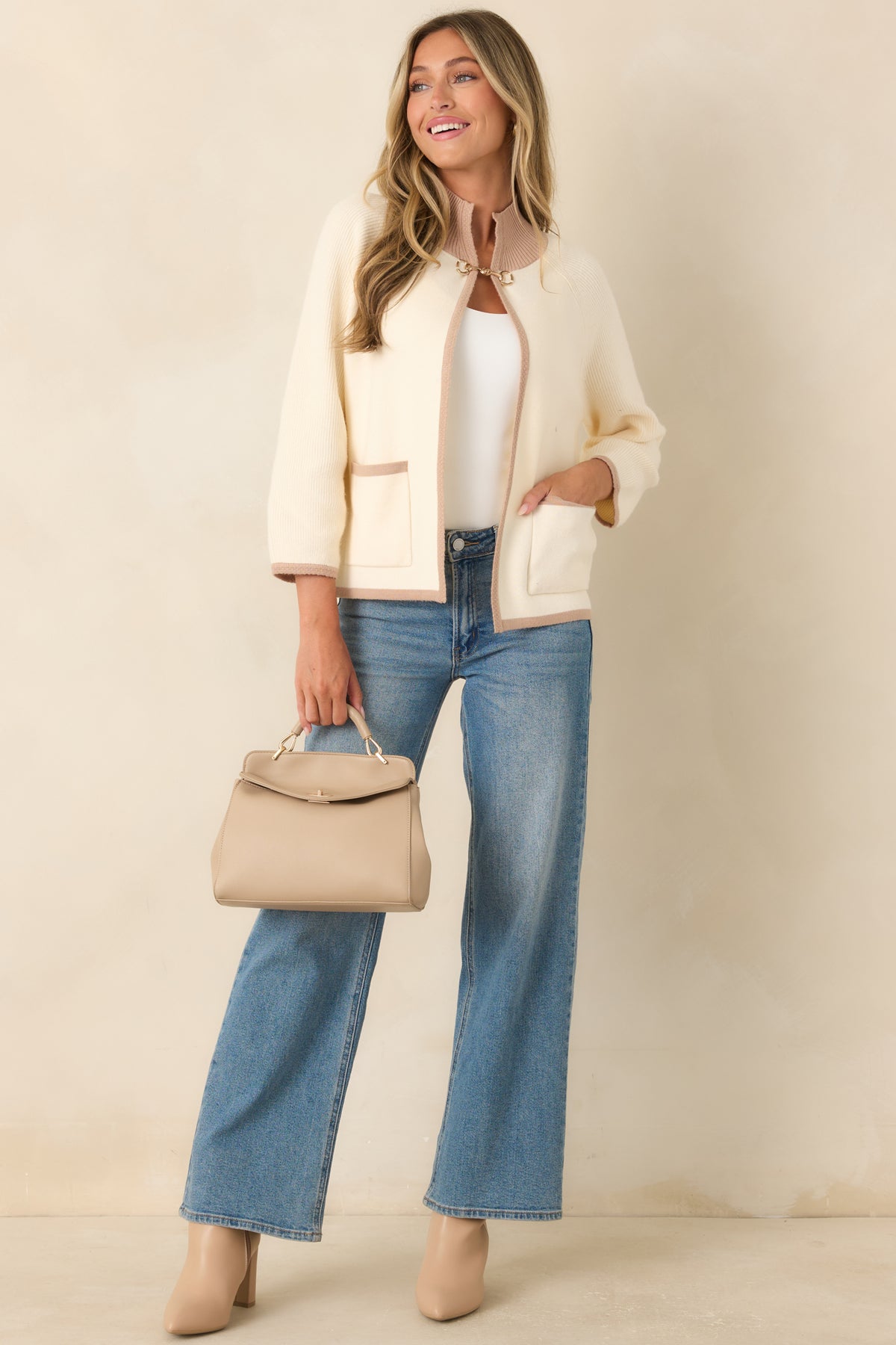 Ivory knit cardigan featuring taupe contrast trim, a relaxed open-front silhouette, patch pockets, ribbed edges, and a polished gold-tone horsebit closure.