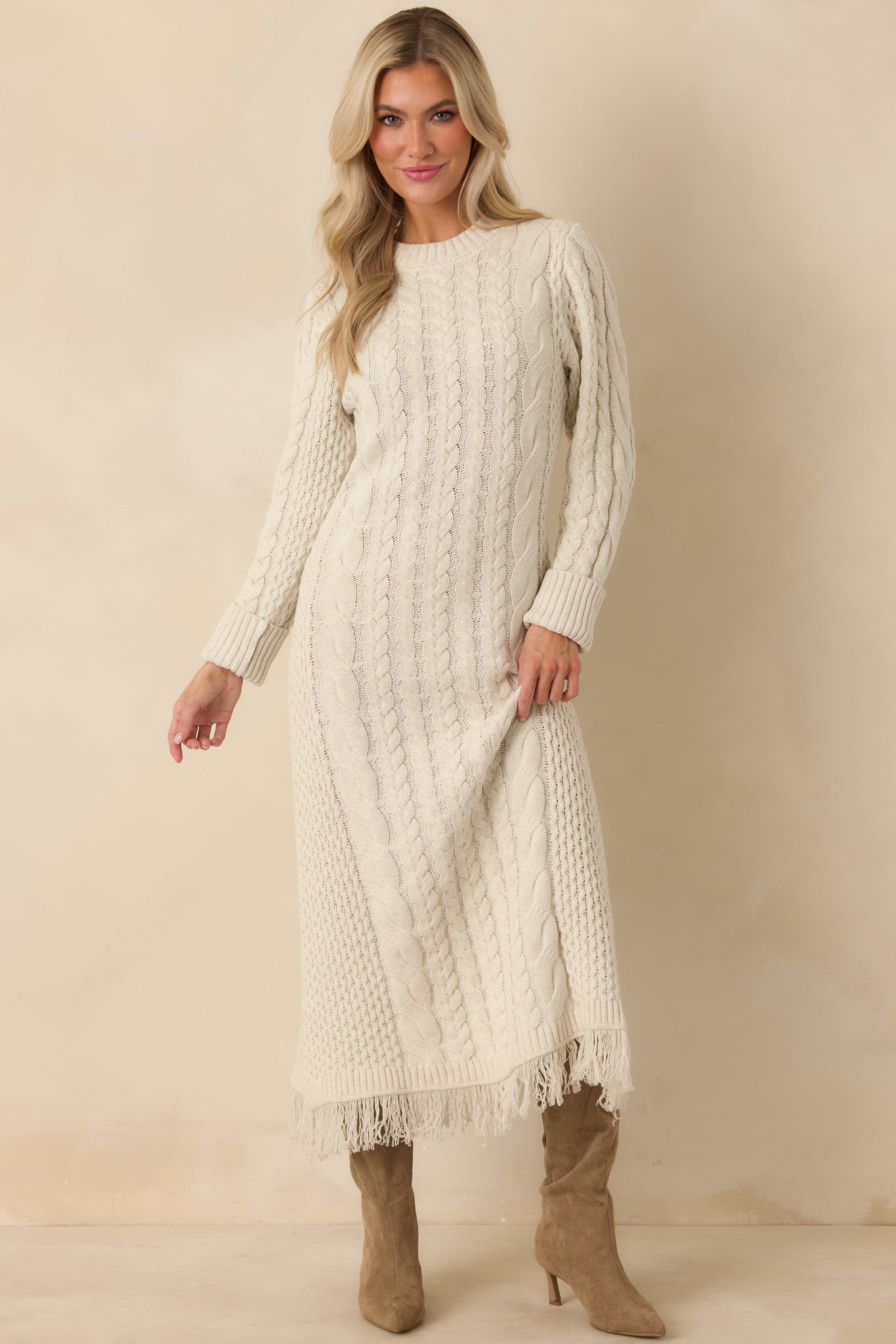 Textured ivory knit maxi dress featuring varied cable patterns, long sleeves, and movement-ready fringe trim.