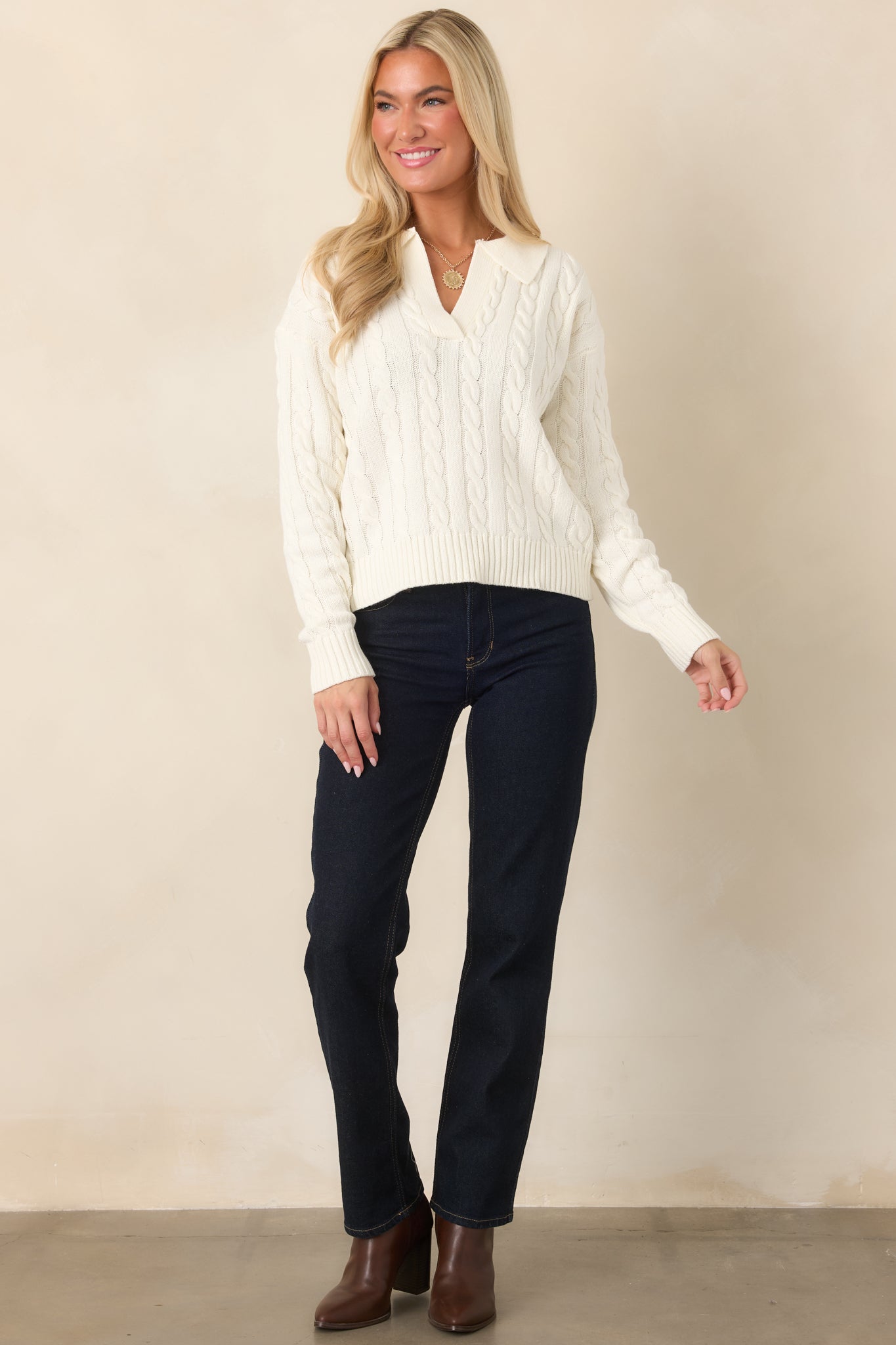 Ivory sweater displaying a richly textured knit construction, classic collar, full-length sleeves, and clean ribbed edging.