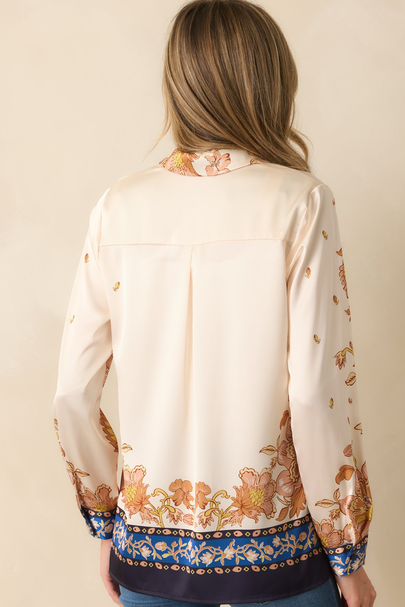 Rear view of the ivory top showing long sleeves, relaxed fit, and full golden yellow floral print with navy trim.