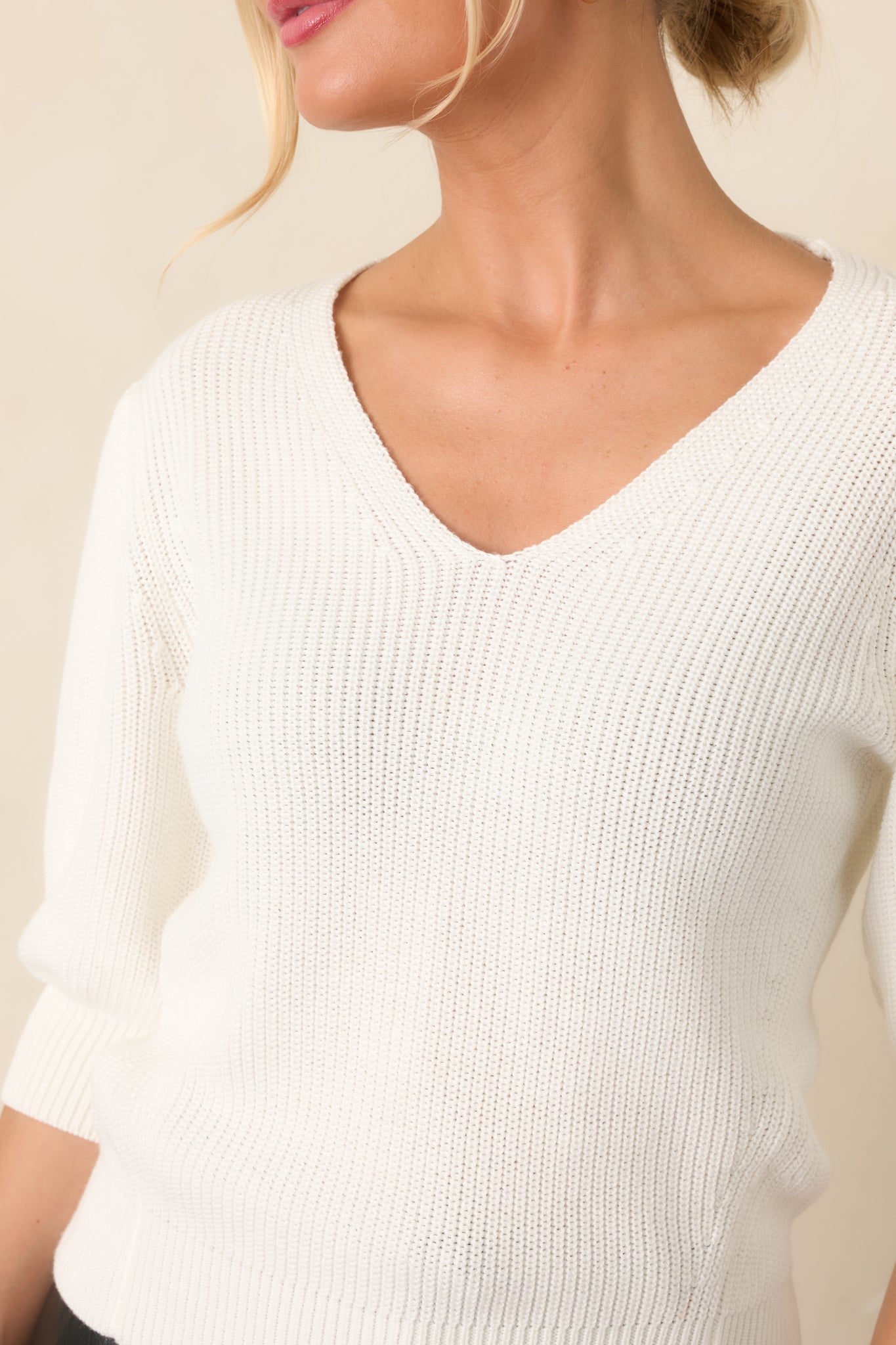 Close-up of the ivory top showing its V-neckline, gathered shoulder detail, and ribbed cuff.