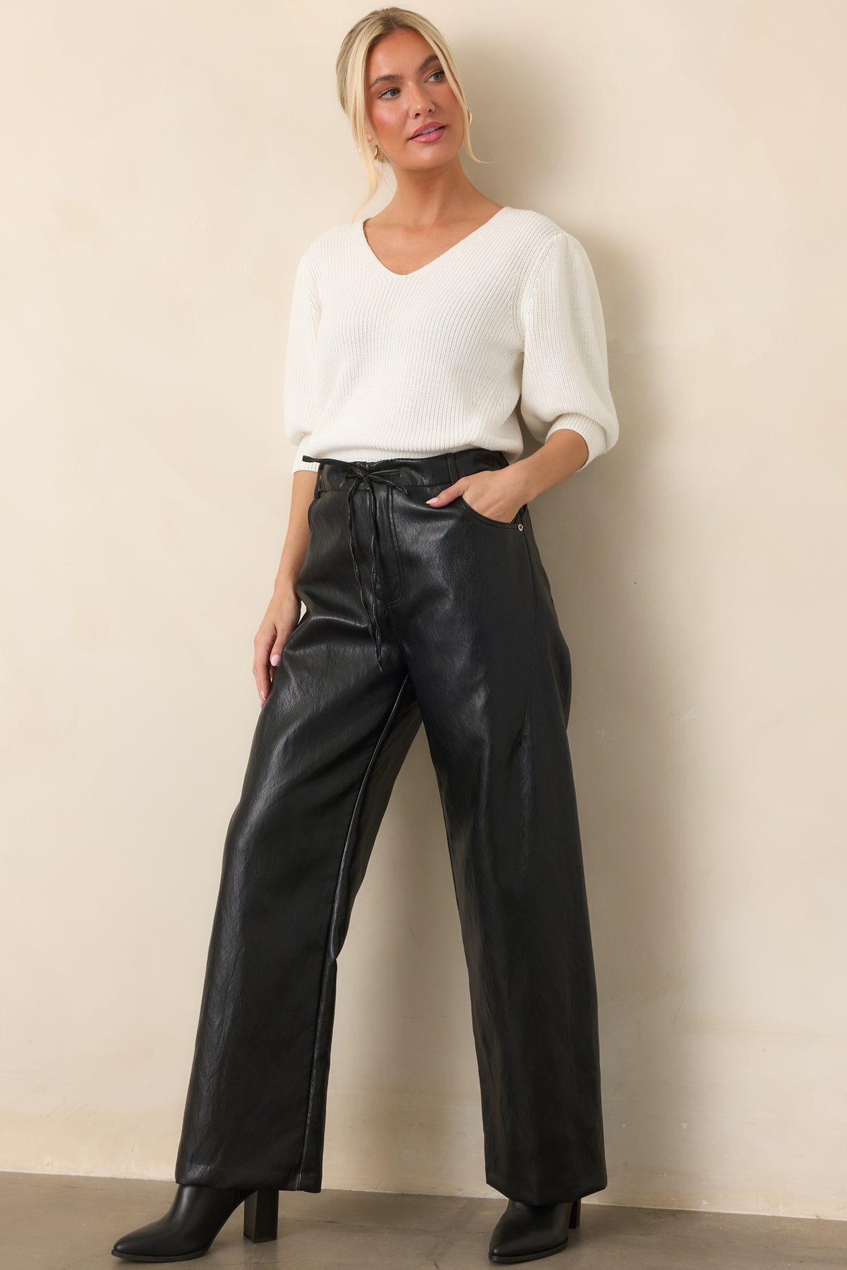 Ivory top highlighting its flattering V-neckline, softly gathered shoulders, wide cuffs, and ribbed hem.