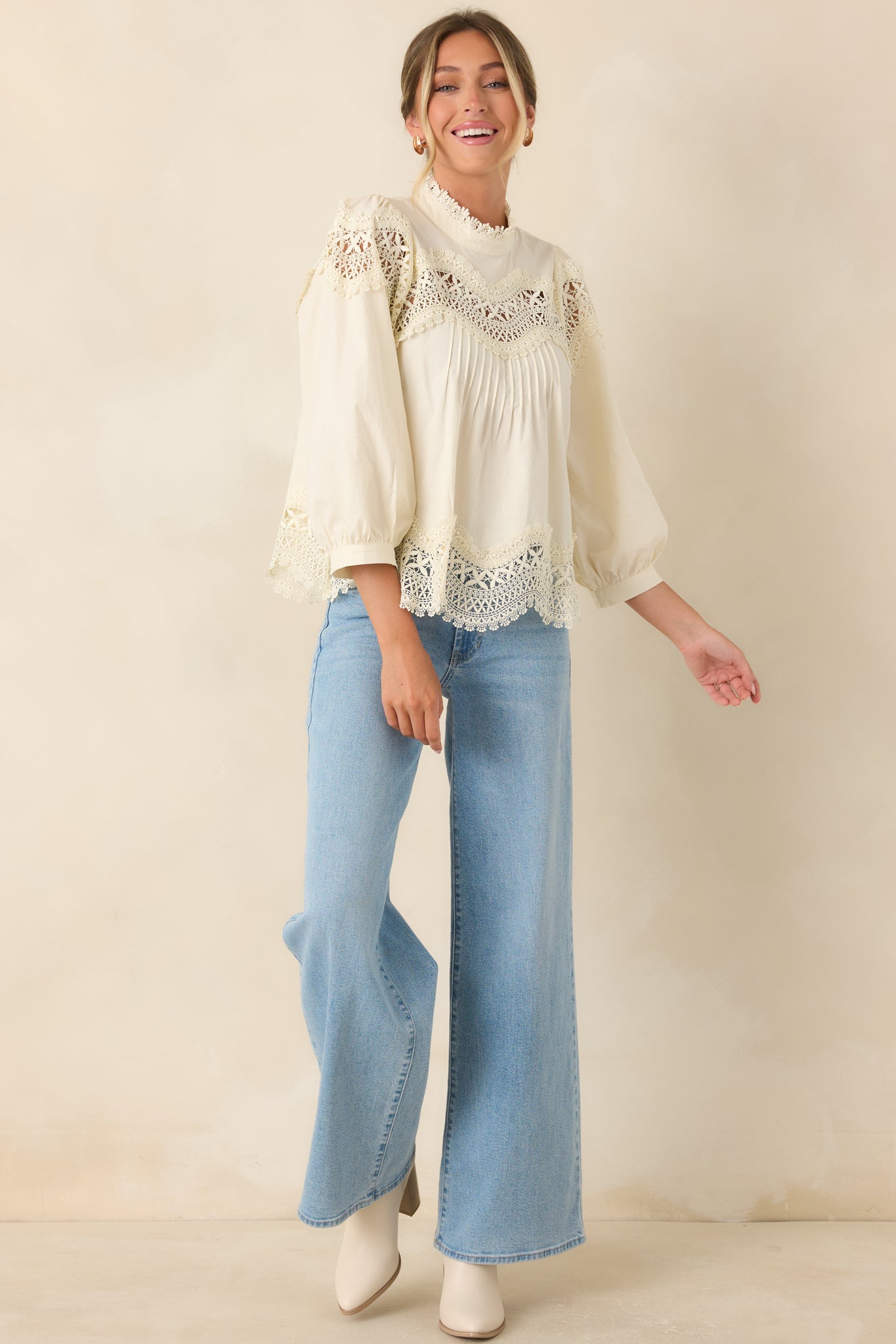 Ivory top featuring a high neckline, balloon sleeves, scalloped details, and a polished relaxed fit.