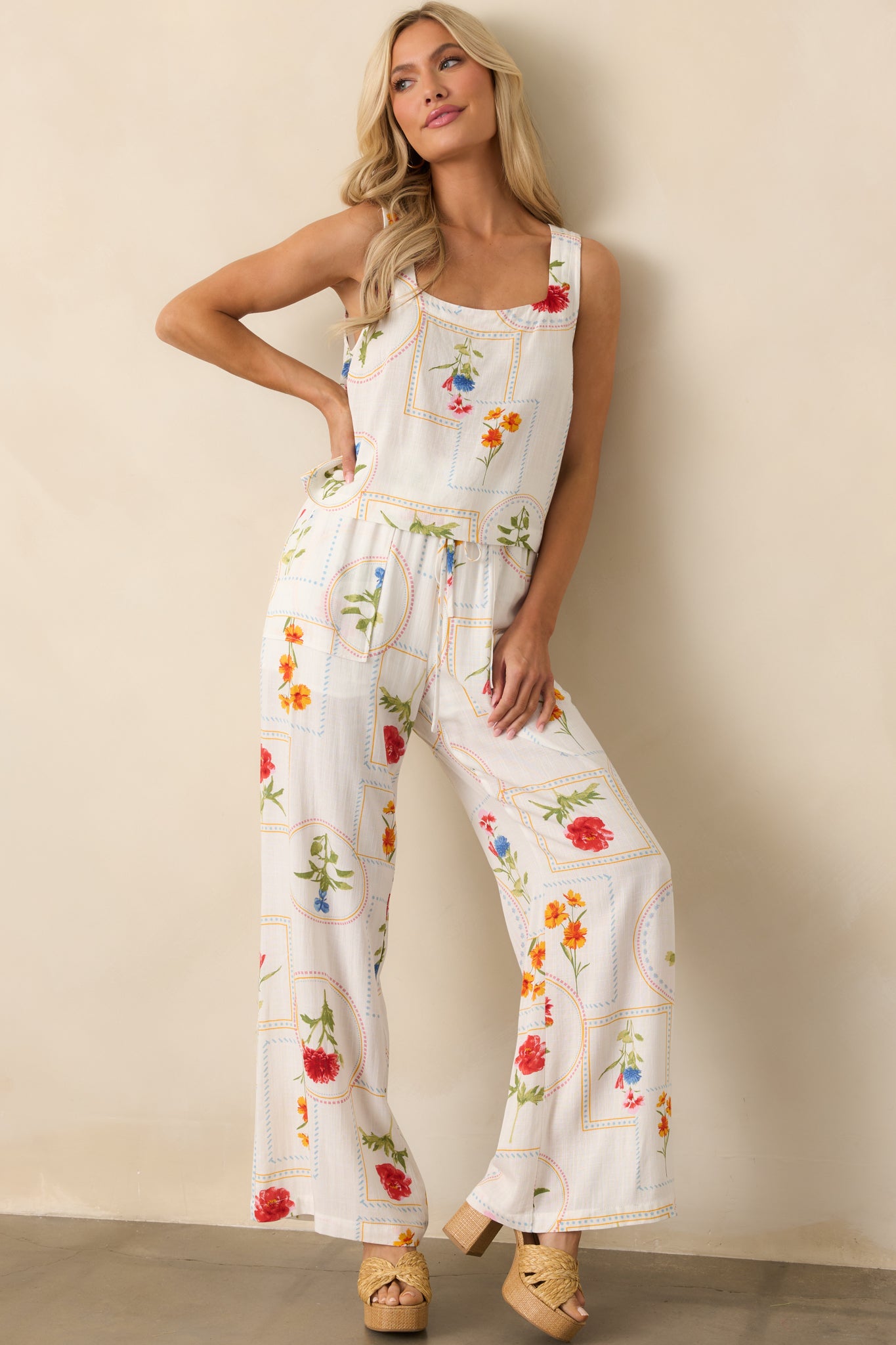 The wide-leg ivory pants featuring a bold geometric floral patchwork pattern, displayed in a casual standing pose.