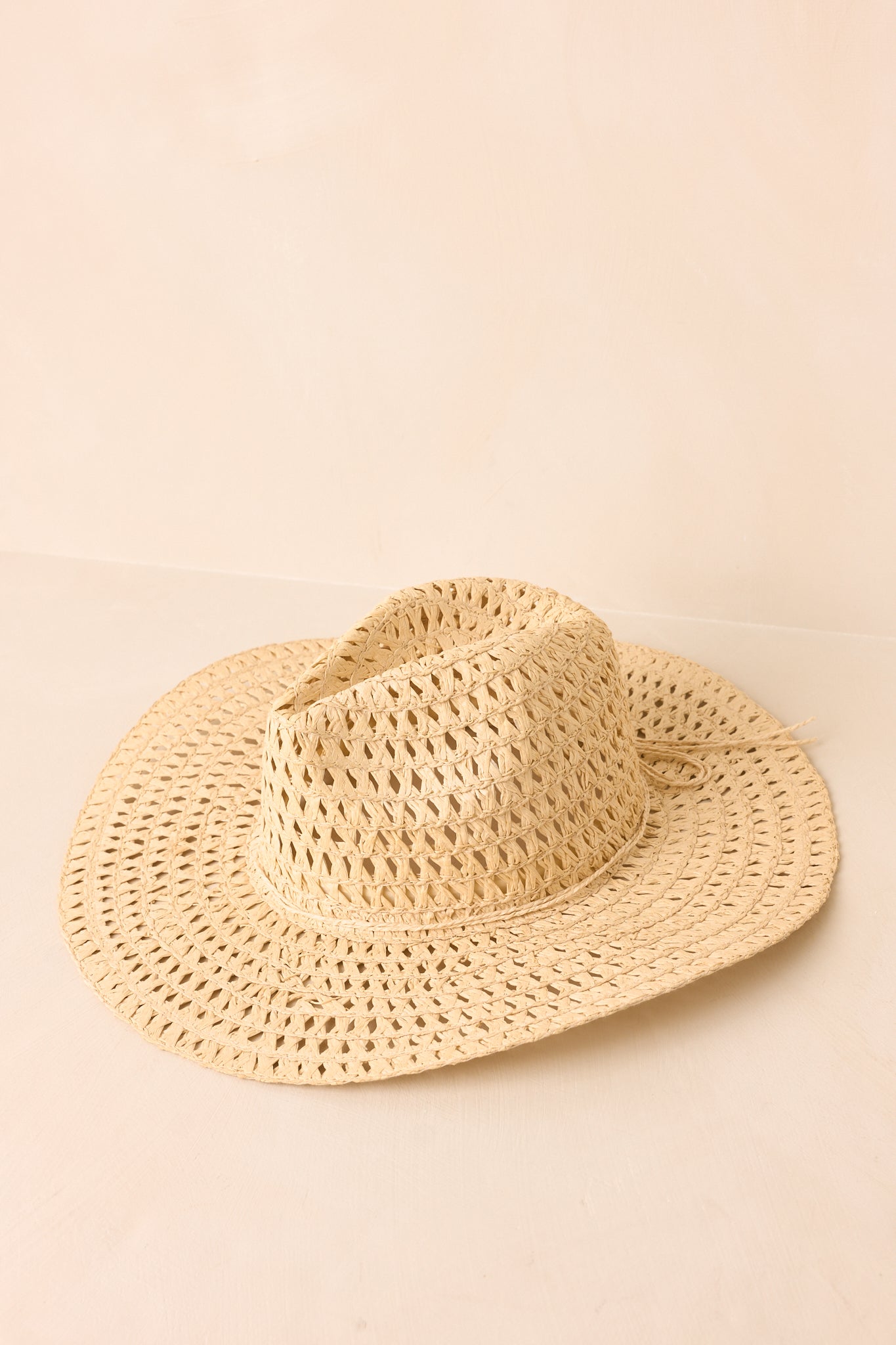 Ivory woven cowboy hat displayed from an angled view featuring an airy straw weave and wide brim.
