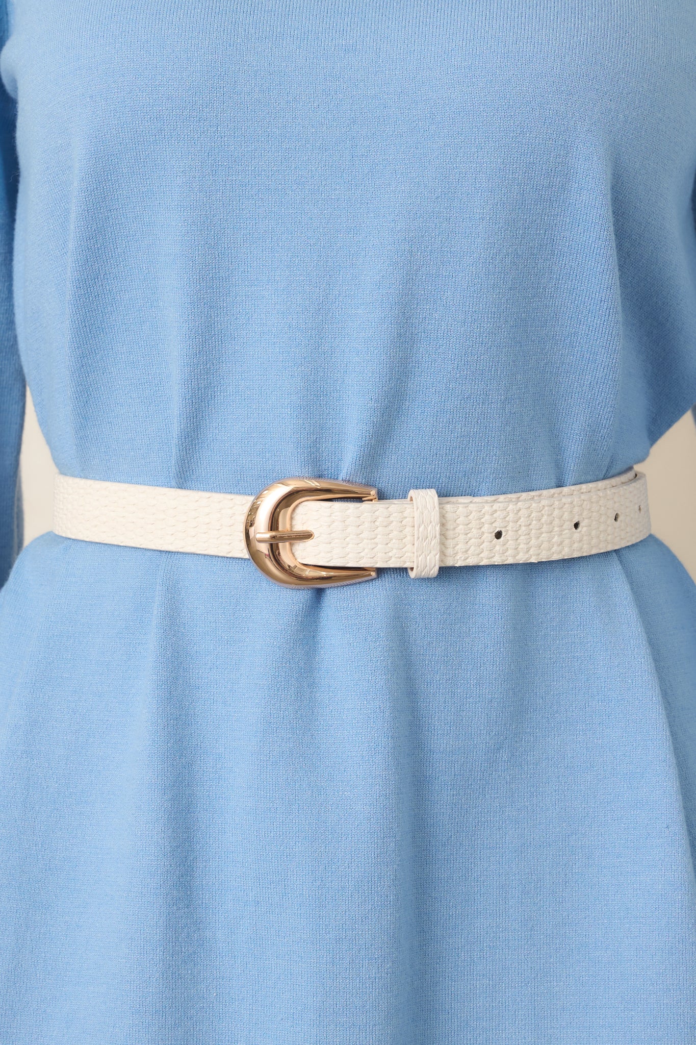 Ivory faux leather belt showcasing the dimensional woven texture along the strap and smooth gold-tone hardware at the fastening end.