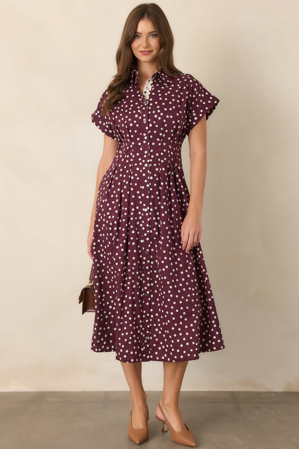 Ivory cotton midi dress with plum polka dots, a collared neckline, button-front closure, short sleeves, waist-defining seams, and side pockets.