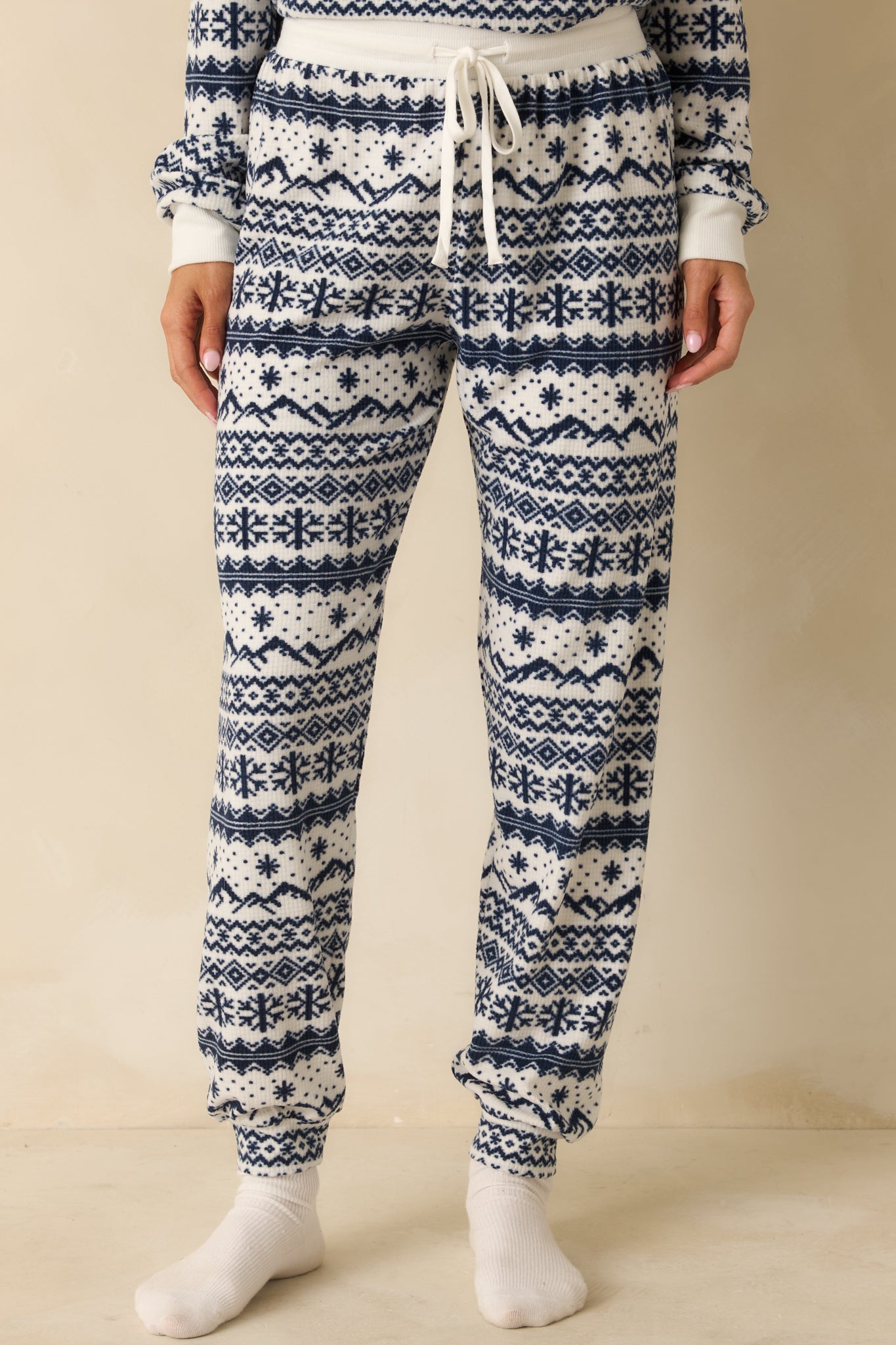 Ivory and navy jogger pants cropped mid-leg, highlighting relaxed fit, cuffed hems, and Fair Isle pattern.