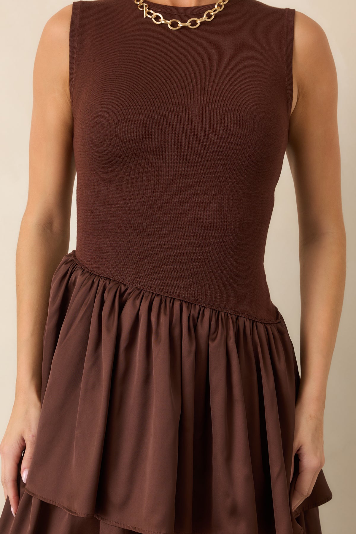 Close-up highlights the transition between the fitted knit bodice, diagonal waist seam, and textured woven layers.