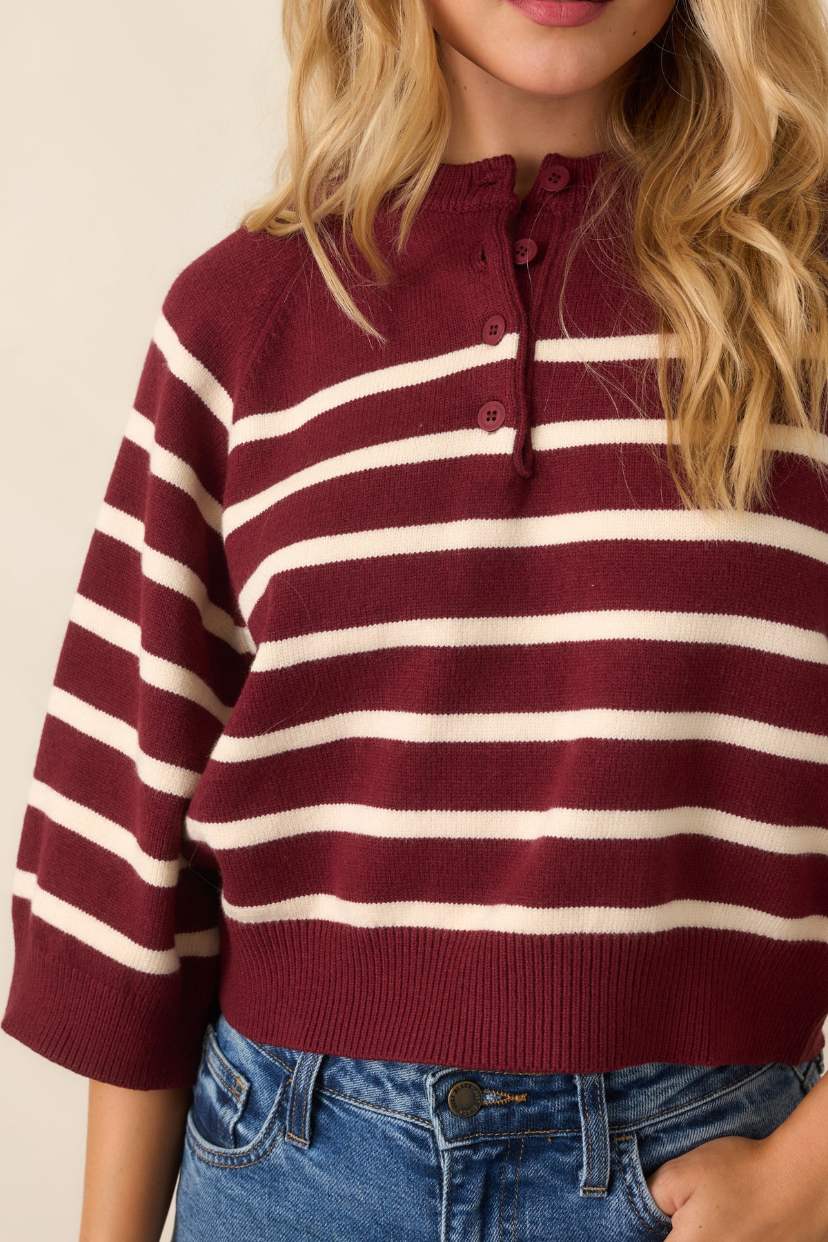 Close-up detail of the knit top showing the button placket and ribbed neckline trim.