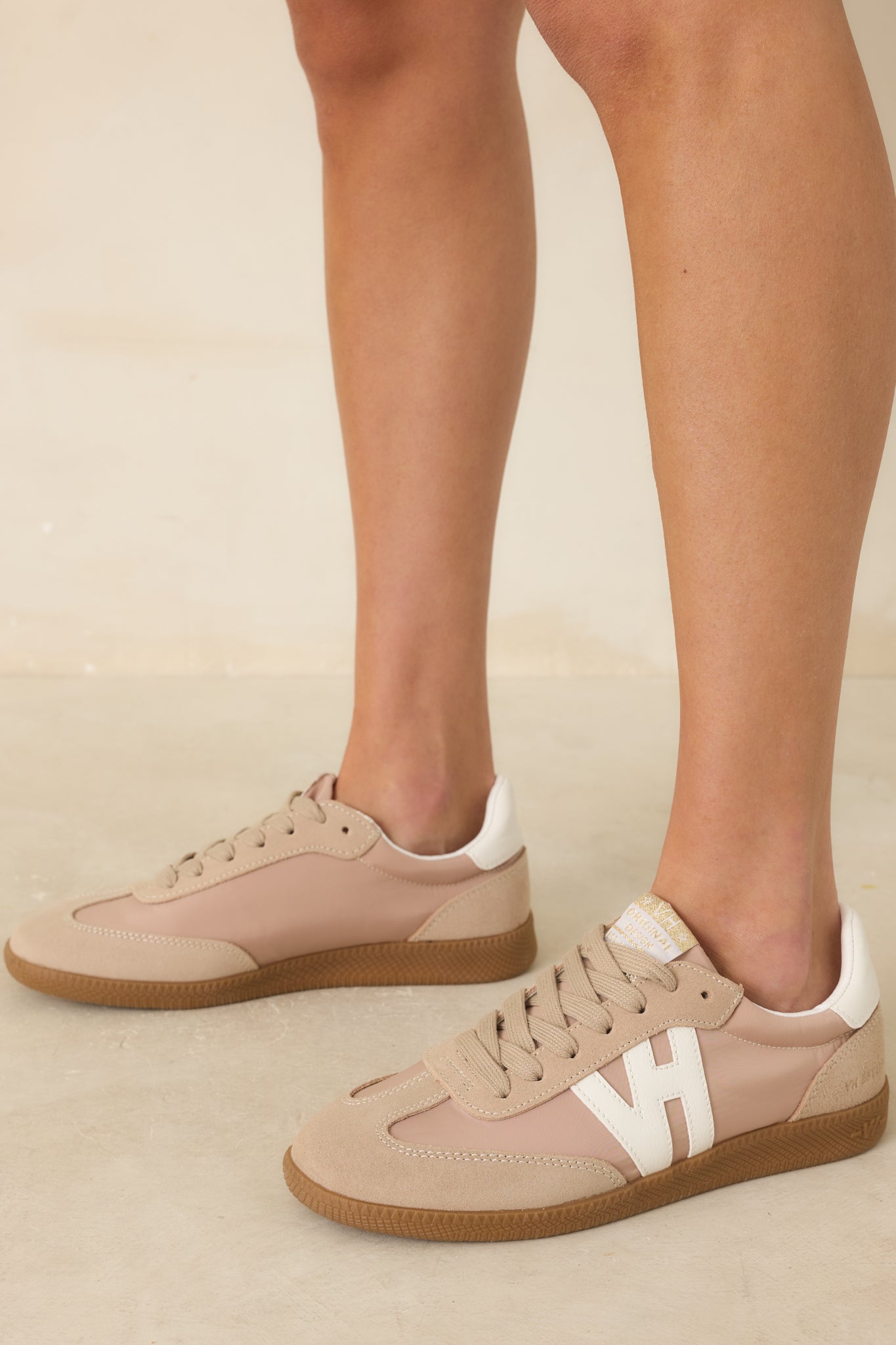 Lace-up sneakers with standard white laces and a clean, low-profile silhouette displayed against a beige background.