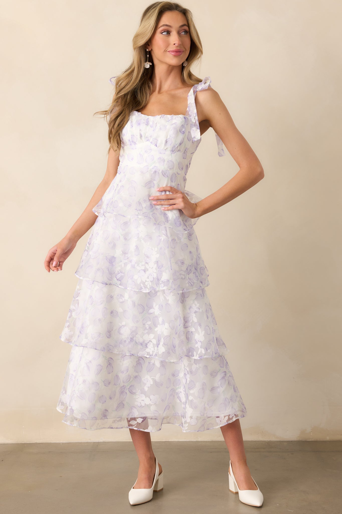 A lavender midi dress with a white lining and a delicate tulip and floral tulle overlay. The sweetheart neckline and tiered skirt create a soft, romantic silhouette.