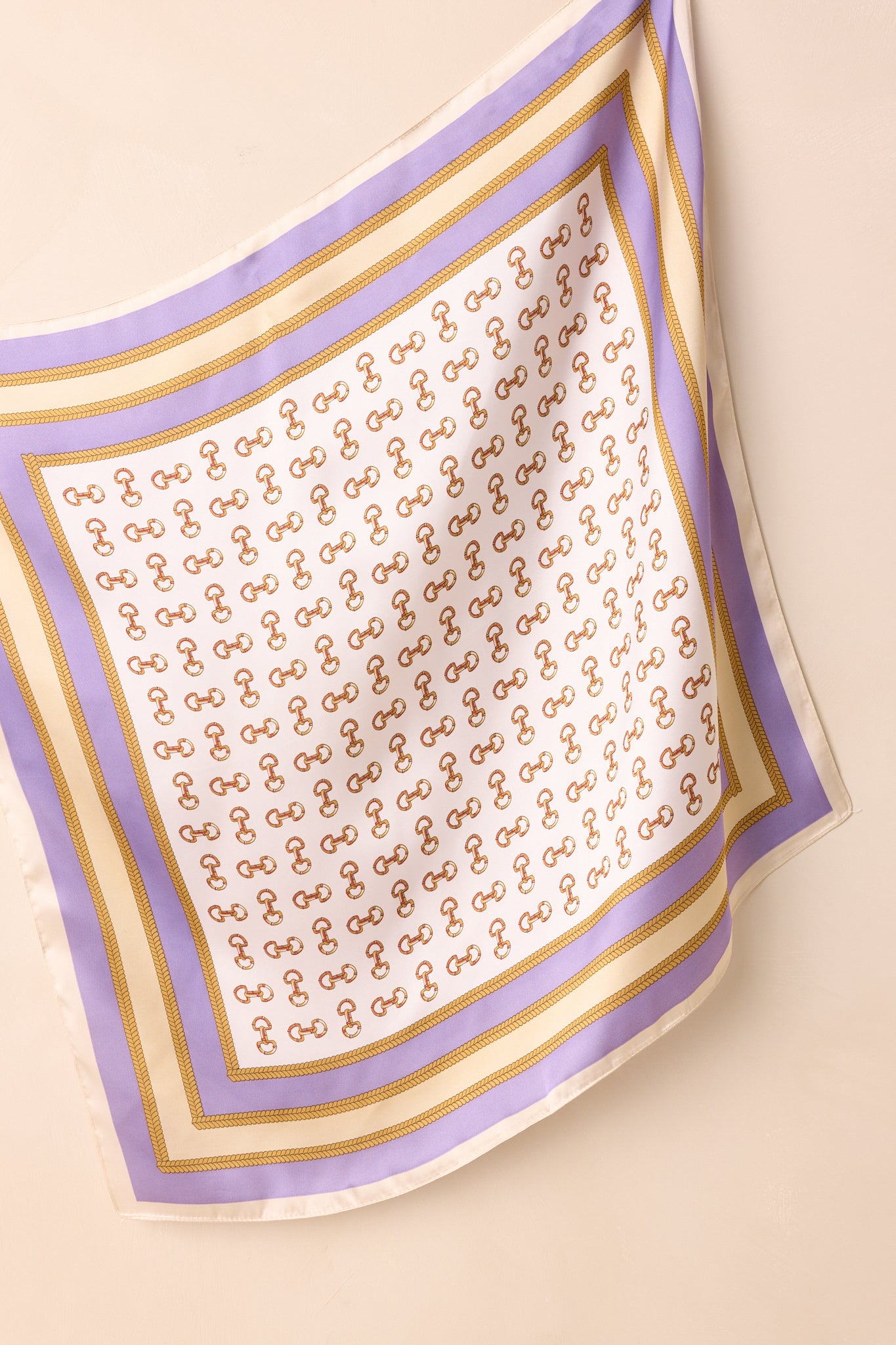 Full view of the lavender scarf featuring an allover gold snaffle bit pattern with lavender and gold chain border detailing.