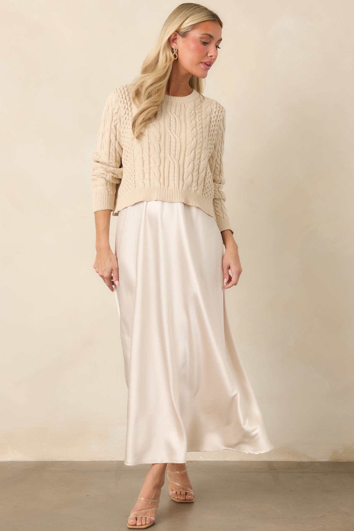 Layered satin maxi dress showcasing its flowing silhouette with a cropped cotton sweater and intricate knit texture.

