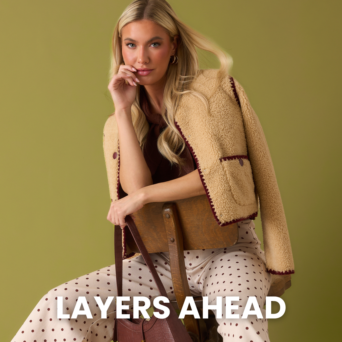 Model wearing brown jacket and white polka dot pants. Text reads: "Layers Ahead."