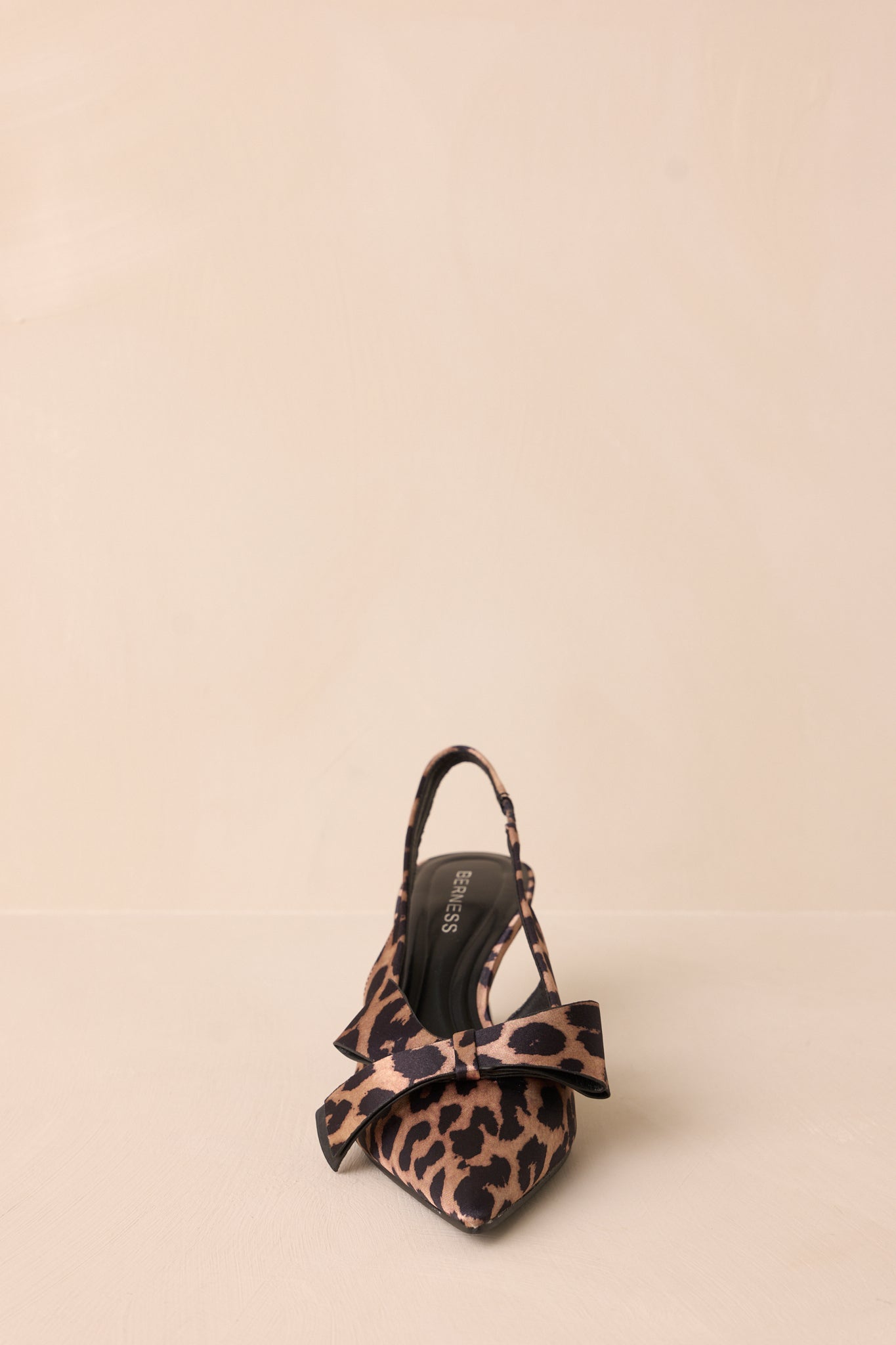 The back view of the leopard heels, highlighting the slingback strap and the large bow detail, demonstrating the combination of comfort and style.