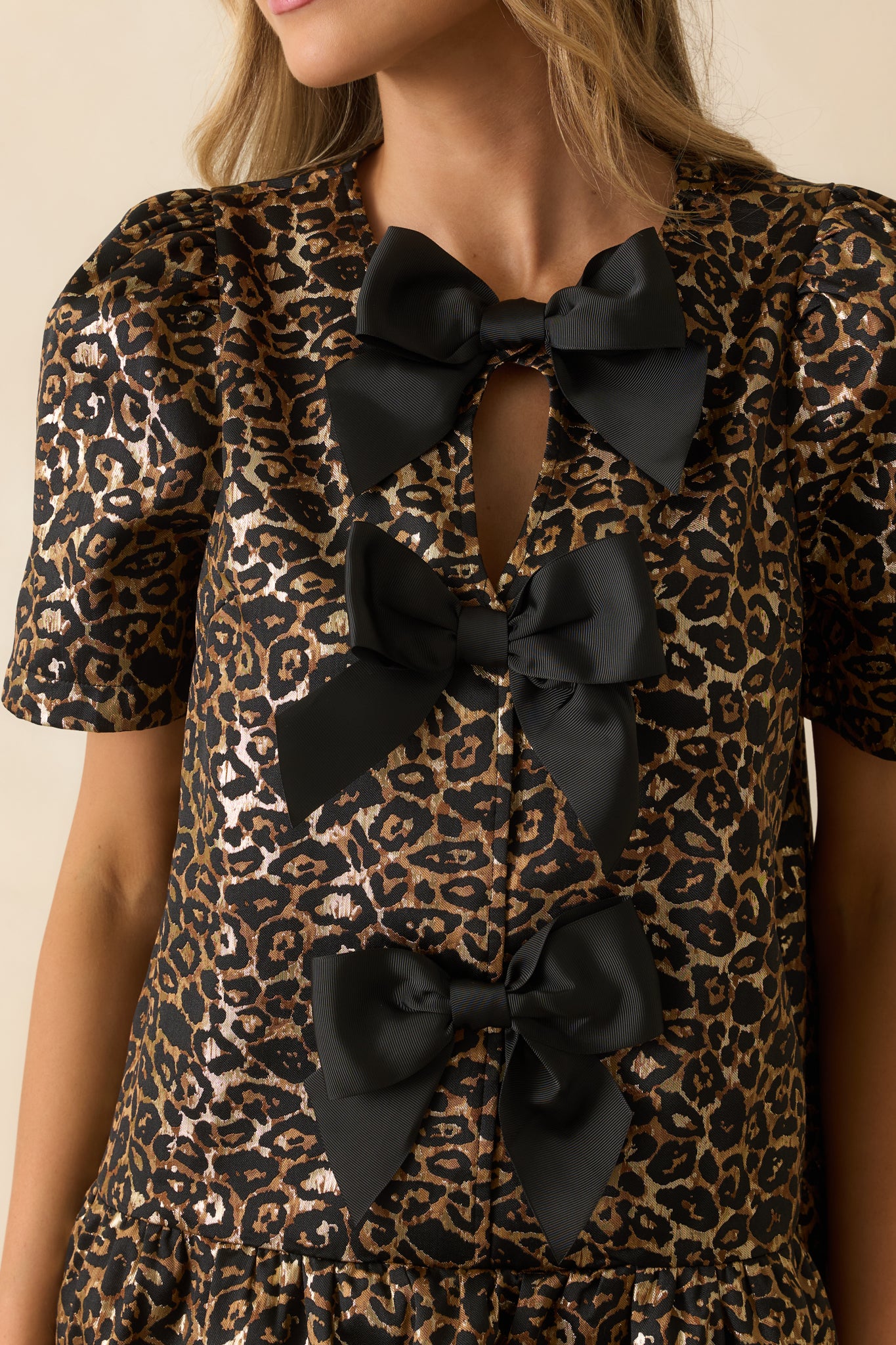 Detailed look at the leopard print fabric, three-bow buttons, and fine stitching of the mini dress.